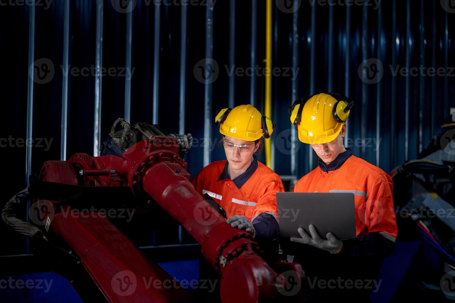 group of male engineer workers maintenance automatic robotic arm machine in a dark room factory. worker checking and repairing automatic robot hand machine. Worker wearing safety glasses and helmet. photo