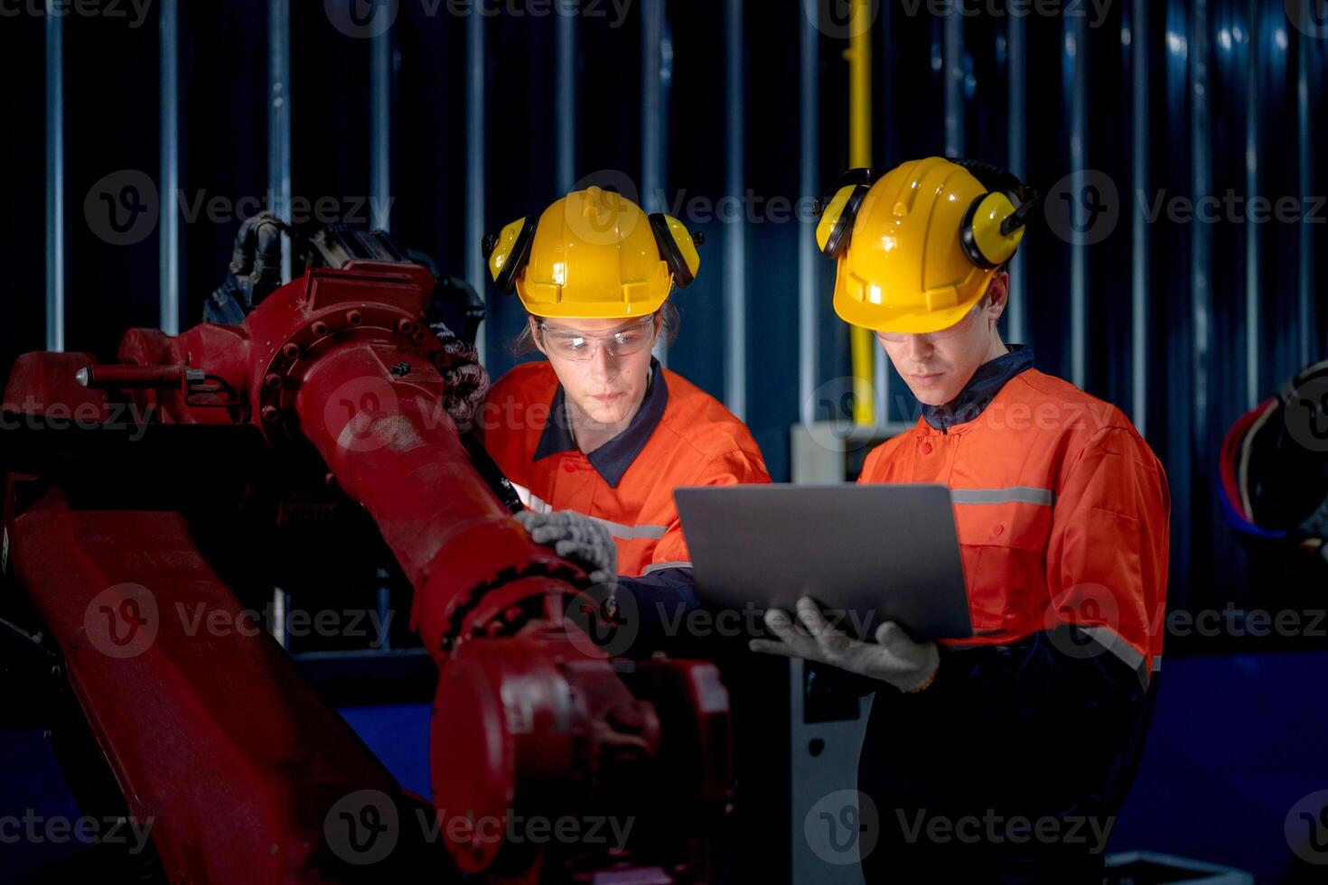 group of male engineer workers maintenance automatic robotic arm machine in a dark room factory. worker checking and repairing automatic robot hand machine. Worker wearing safety glasses and helmet. photo