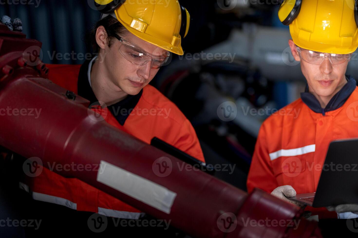 group of male engineer workers maintenance automatic robotic arm machine in a dark room factory. worker checking and repairing automatic robot hand machine. Worker wearing safety glasses and helmet. photo