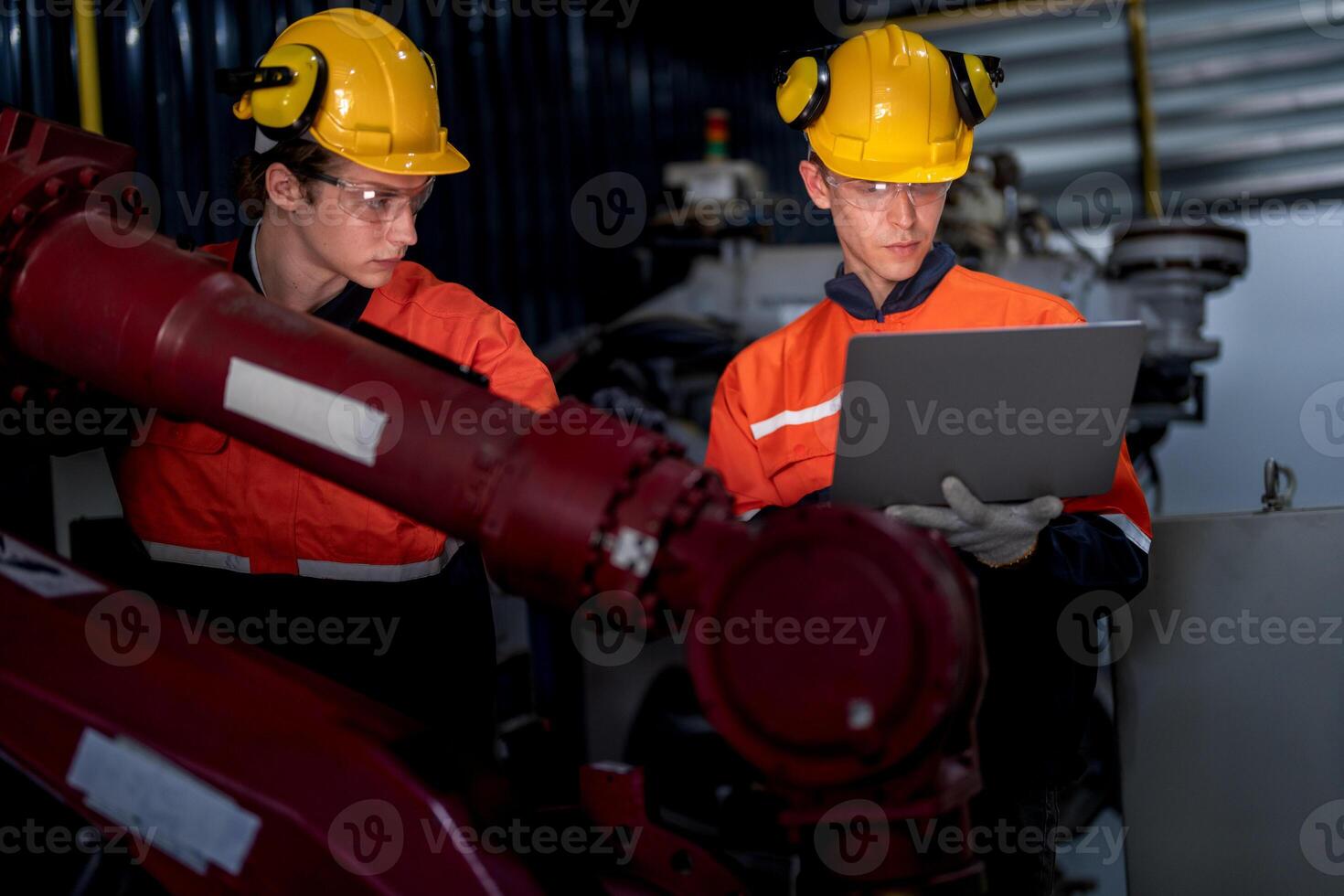 group of male engineer workers maintenance automatic robotic arm machine in a dark room factory. worker checking and repairing automatic robot hand machine. Worker wearing safety glasses and helmet. photo