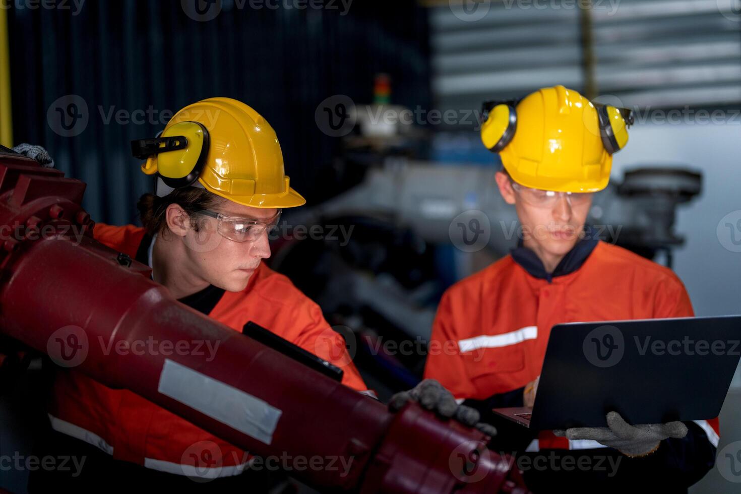 group of male engineer workers maintenance automatic robotic arm machine in a dark room factory. worker checking and repairing automatic robot hand machine. Worker wearing safety glasses and helmet. photo