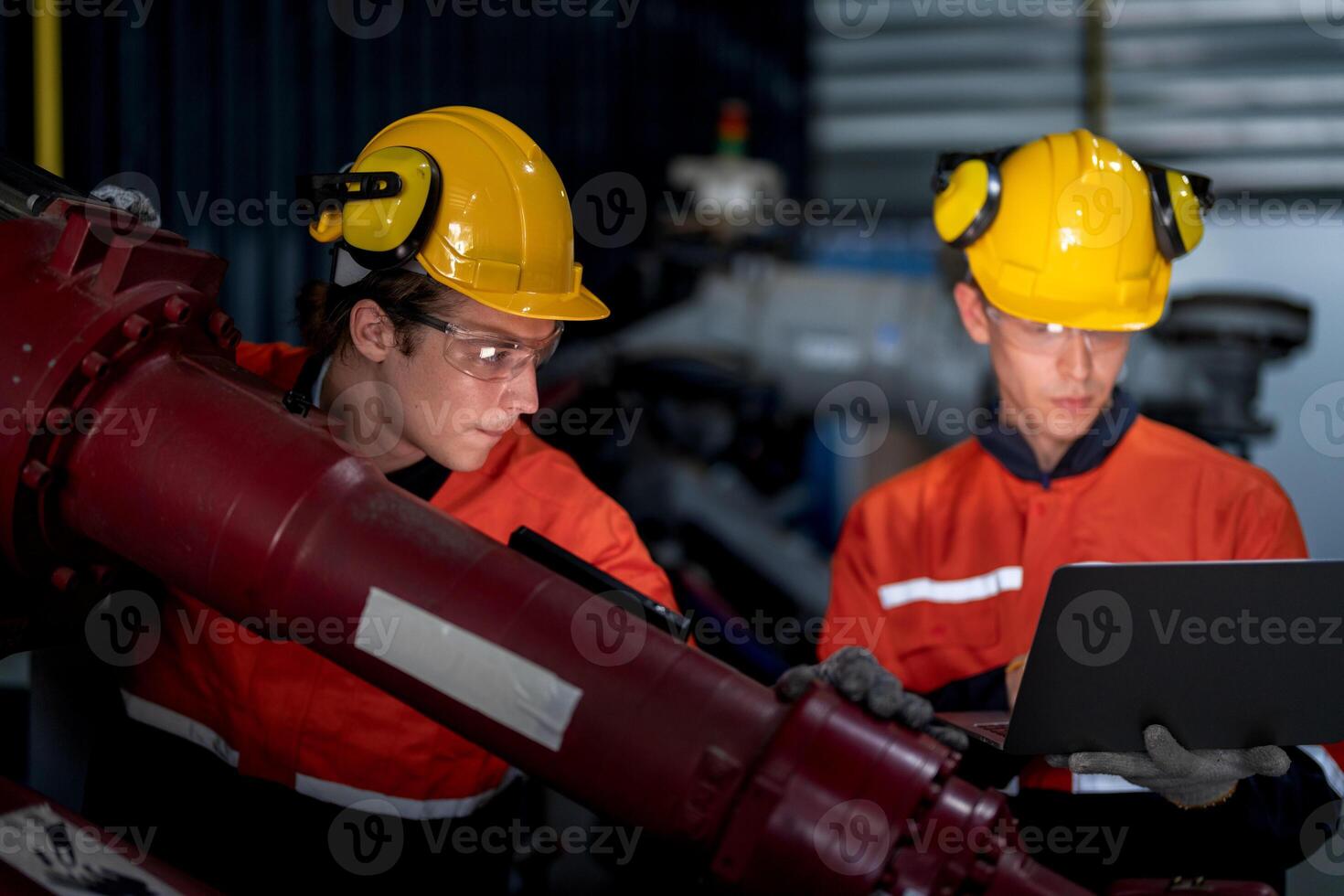 group of male engineer workers maintenance automatic robotic arm machine in a dark room factory. worker checking and repairing automatic robot hand machine. Worker wearing safety glasses and helmet. photo