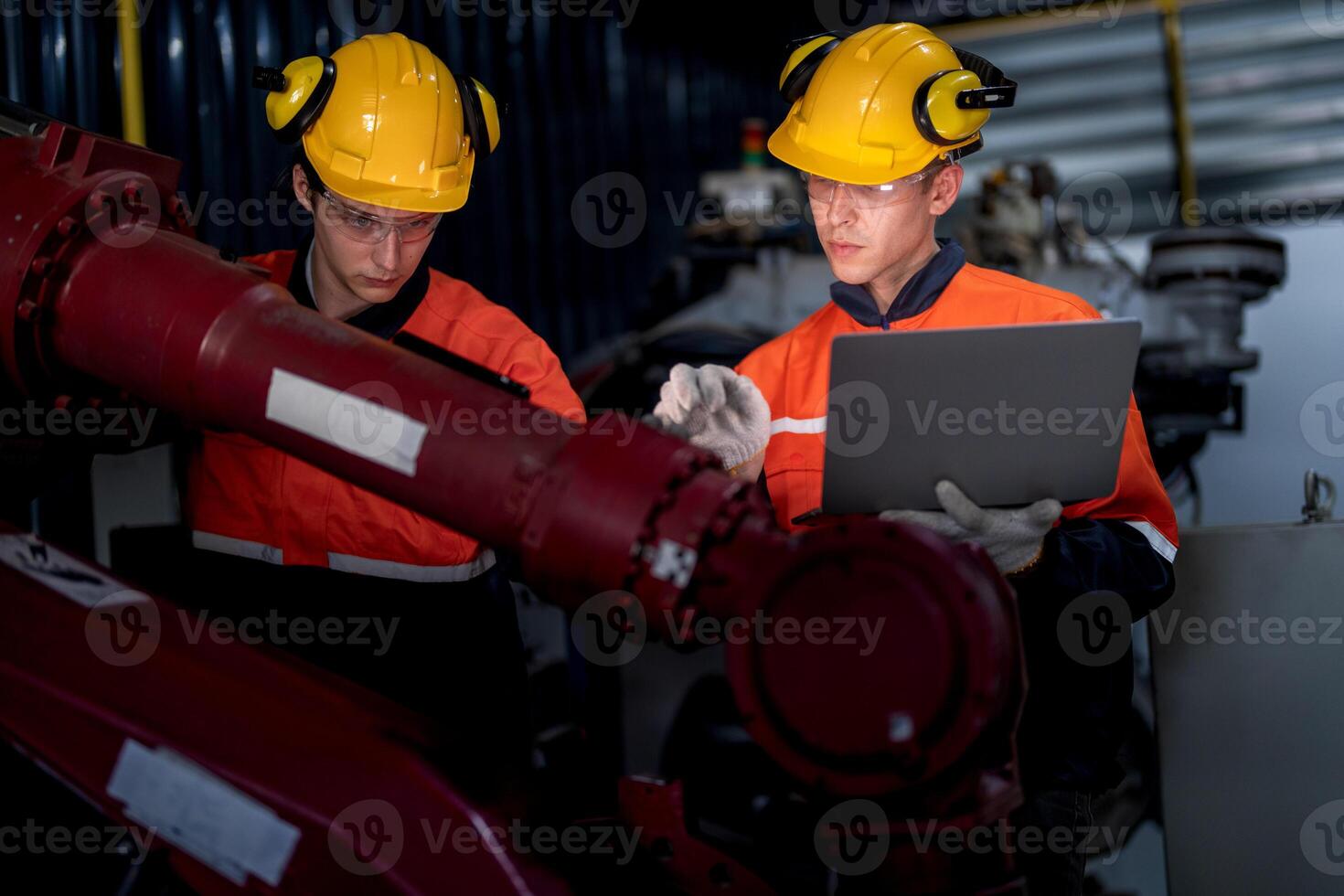 group of male engineer workers maintenance automatic robotic arm machine in a dark room factory. worker checking and repairing automatic robot hand machine. Worker wearing safety glasses and helmet. photo