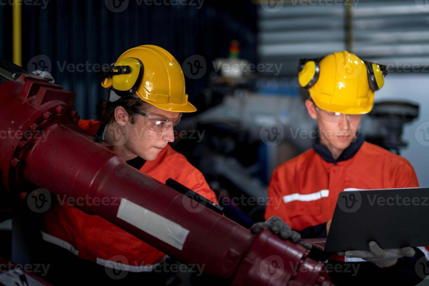 group of male engineer workers maintenance automatic robotic arm machine in a dark room factory. worker checking and repairing automatic robot hand machine. Worker wearing safety glasses and helmet. photo