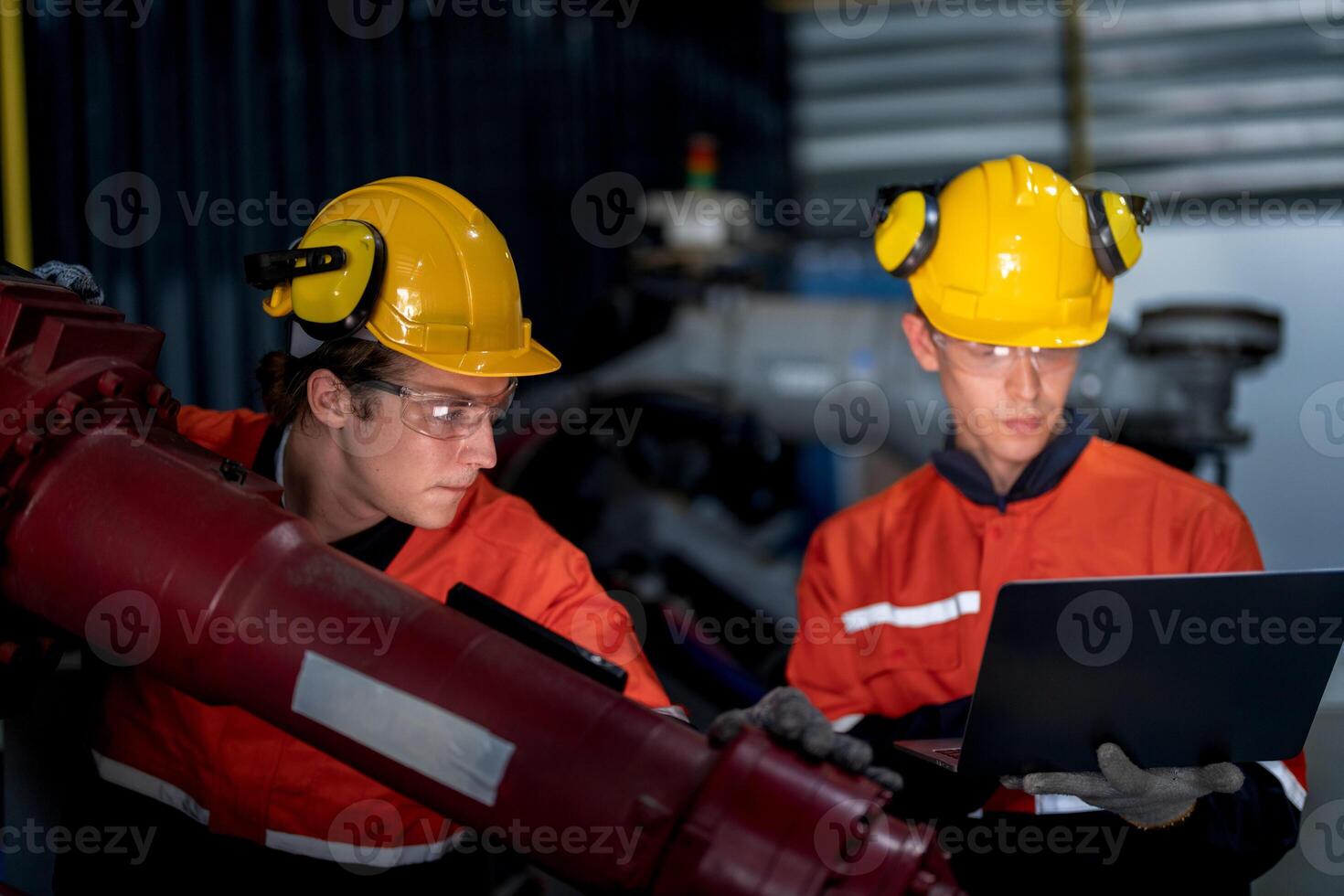 group of male engineer workers maintenance automatic robotic arm machine in a dark room factory. worker checking and repairing automatic robot hand machine. Worker wearing safety glasses and helmet. photo