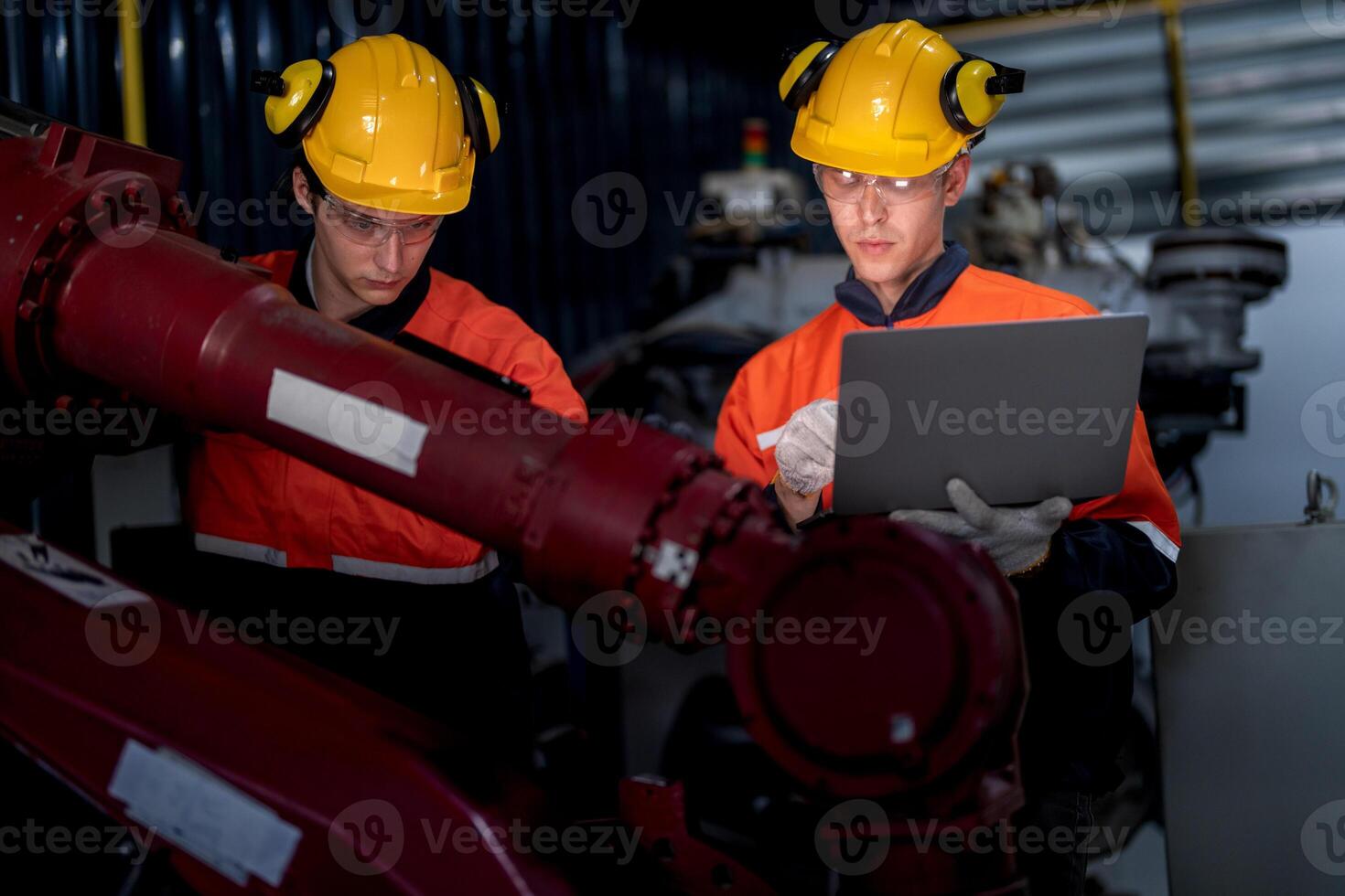 grupo de masculino ingeniero trabajadores mantenimiento automático robótico brazo máquina en un oscuro habitación fábrica. trabajador comprobación y reparando automático robot mano máquina. trabajador vistiendo la seguridad lentes y casco. foto