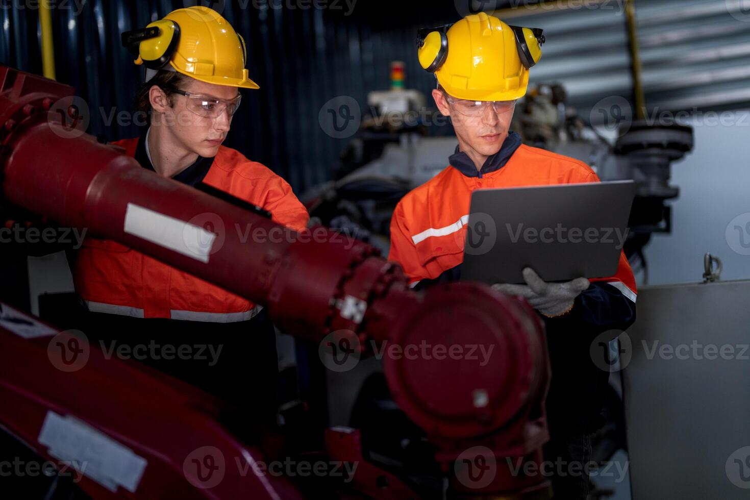 group of male engineer workers maintenance automatic robotic arm machine in a dark room factory. worker checking and repairing automatic robot hand machine. Worker wearing safety glasses and helmet. photo