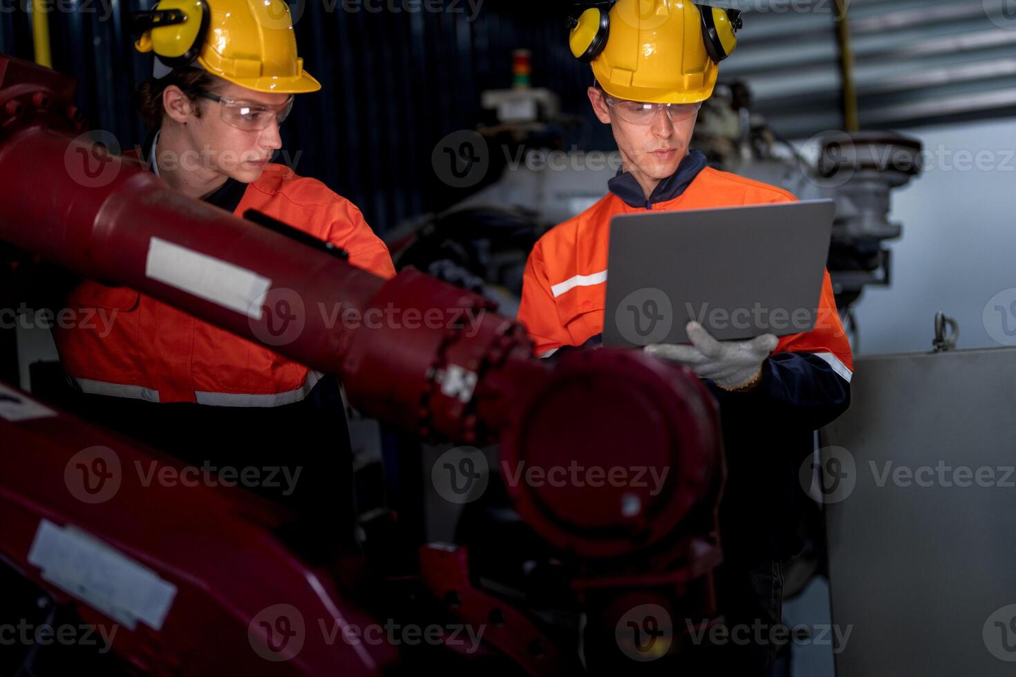 group of male engineer workers maintenance automatic robotic arm machine in a dark room factory. worker checking and repairing automatic robot hand machine. Worker wearing safety glasses and helmet. photo