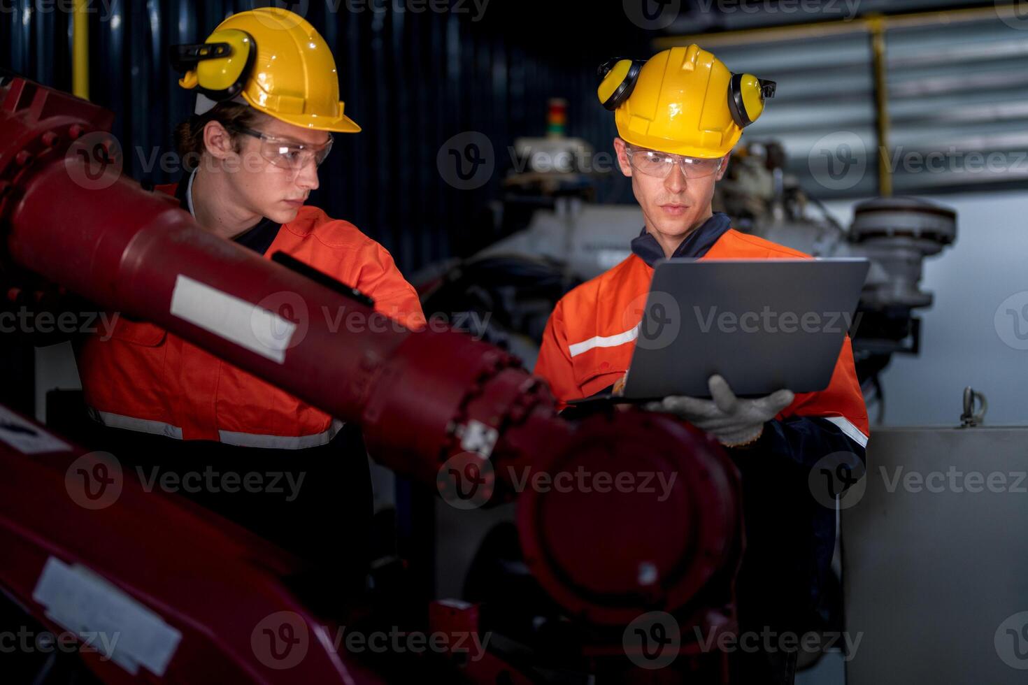 group of male engineer workers maintenance automatic robotic arm machine in a dark room factory. worker checking and repairing automatic robot hand machine. Worker wearing safety glasses and helmet. photo