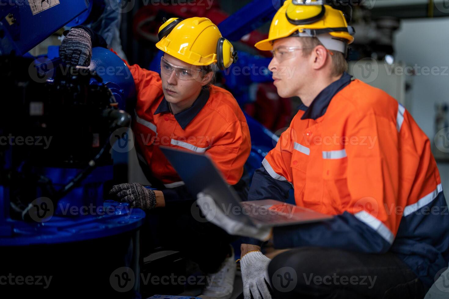 Factory engineers inspecting on machine with smart tablet. Worker works at heavy machine robot arm. The welding machine with a remote system in an industrial factory. Artificial intelligence concept. photo