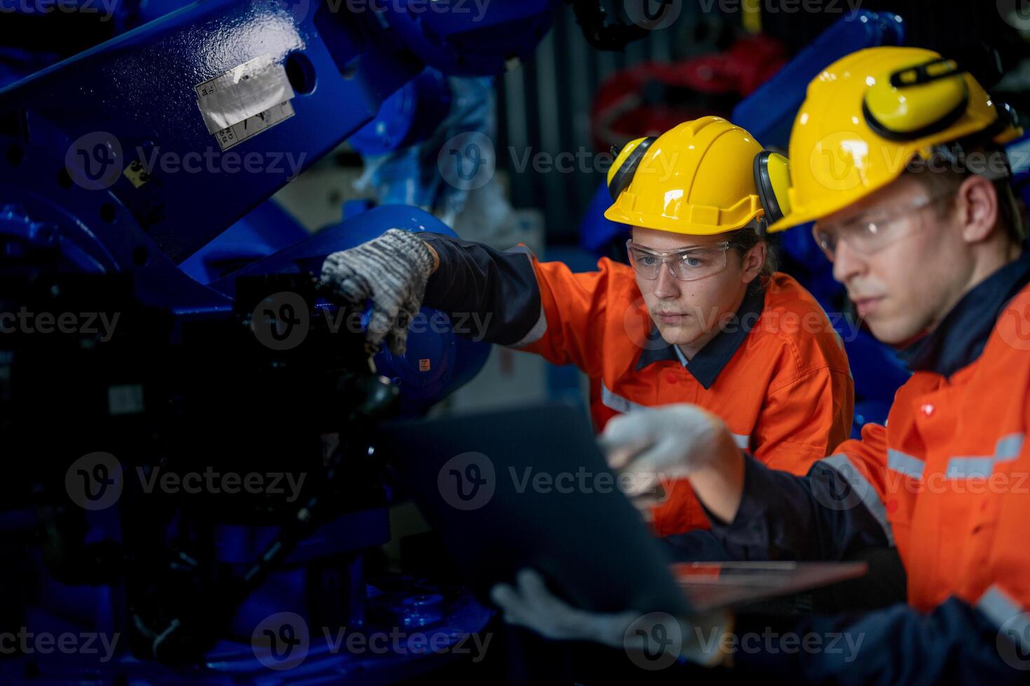 Factory engineers inspecting on machine with smart tablet. Worker works at heavy machine robot arm. The welding machine with a remote system in an industrial factory. Artificial intelligence concept. photo
