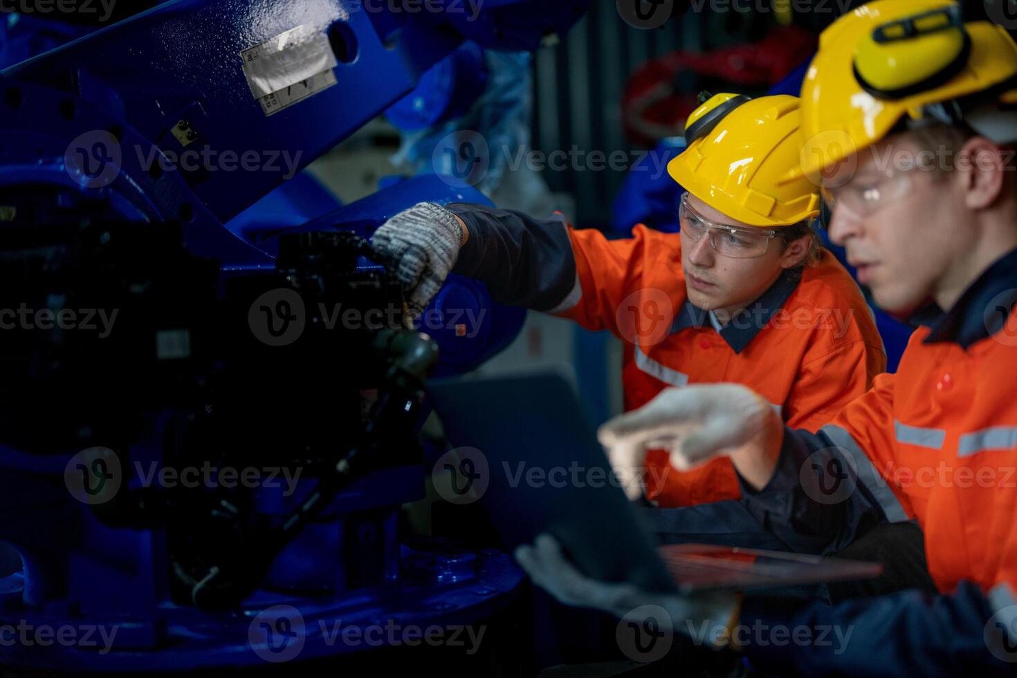 Factory engineers inspecting on machine with smart tablet. Worker works at heavy machine robot arm. The welding machine with a remote system in an industrial factory. Artificial intelligence concept. photo