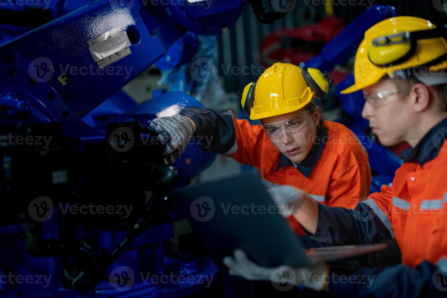 Factory engineers inspecting on machine with smart tablet. Worker works at heavy machine robot arm. The welding machine with a remote system in an industrial factory. Artificial intelligence concept. photo