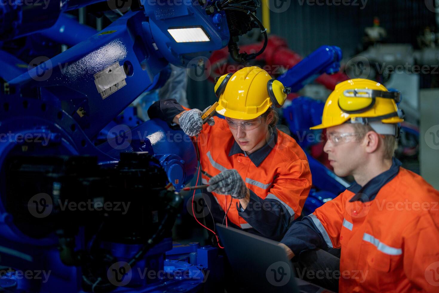 Factory engineers inspecting on machine with smart tablet. Worker works at heavy machine robot arm. The welding machine with a remote system in an industrial factory. Artificial intelligence concept. photo