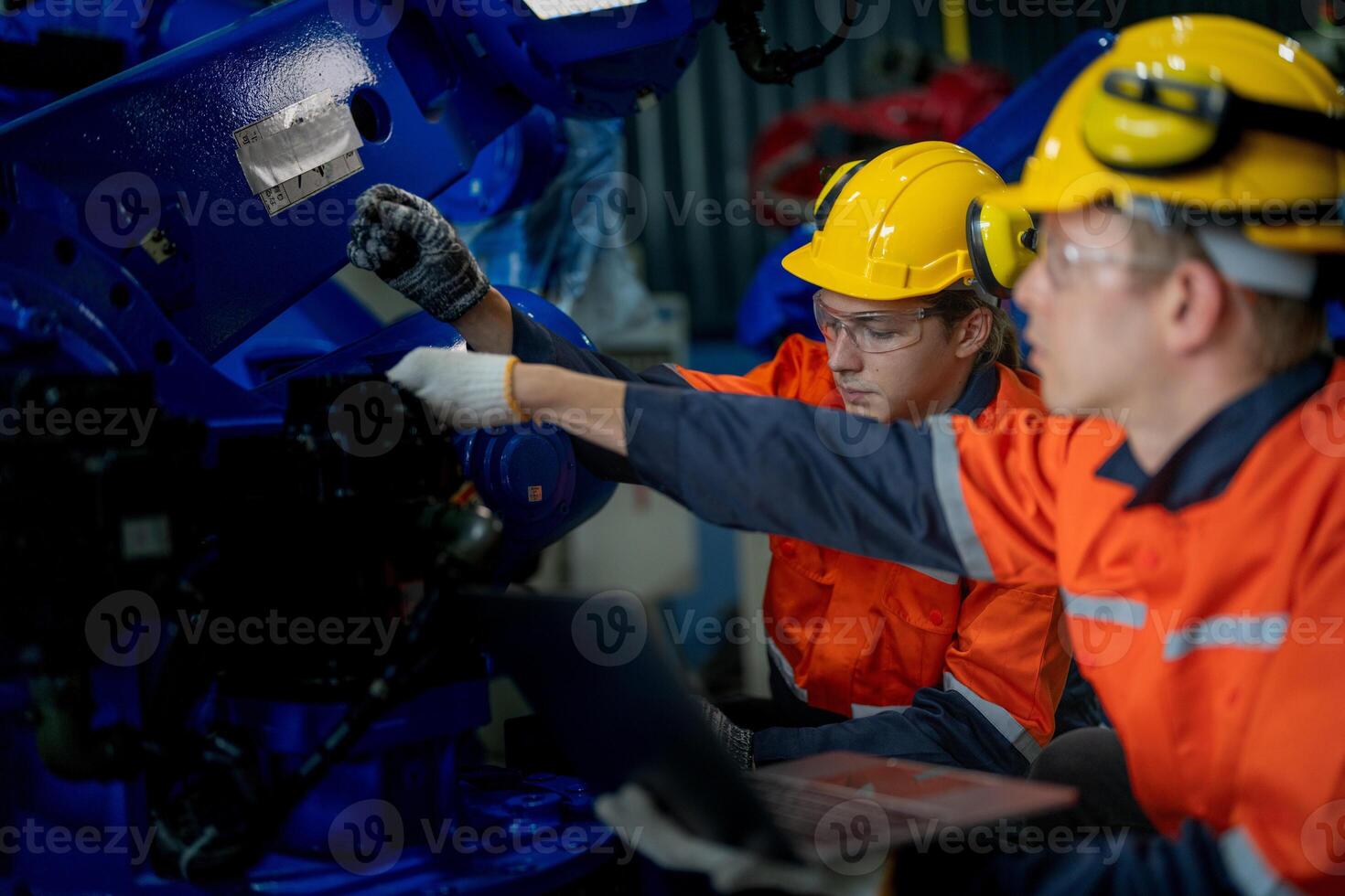 Factory engineers inspecting on machine with smart tablet. Worker works at heavy machine robot arm. The welding machine with a remote system in an industrial factory. Artificial intelligence concept. photo