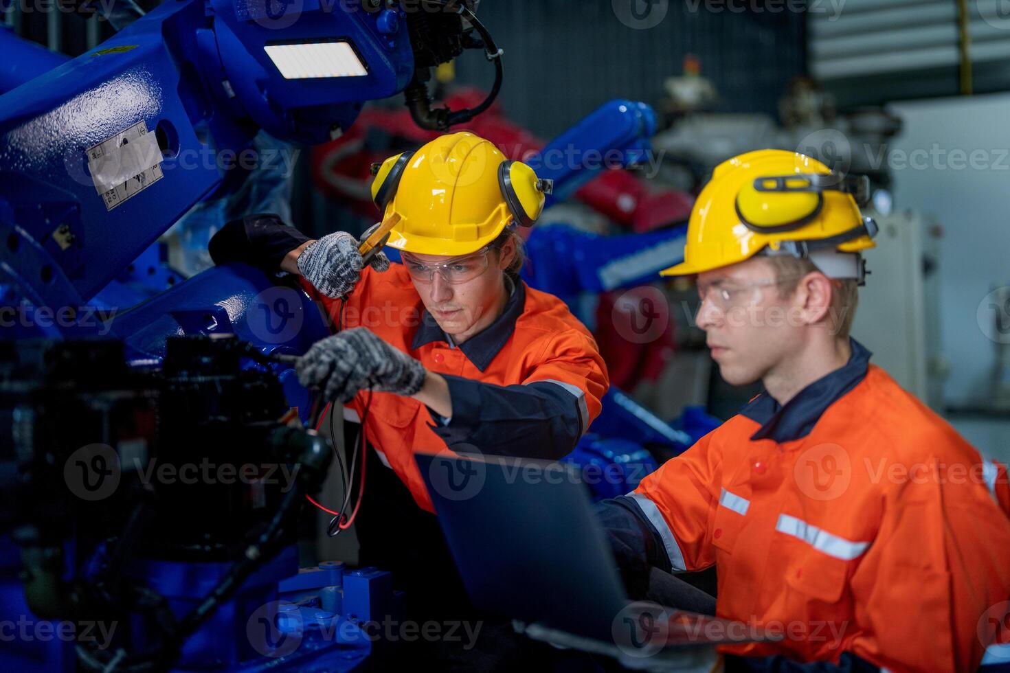 Factory engineers inspecting on machine with smart tablet. Worker works at heavy machine robot arm. The welding machine with a remote system in an industrial factory. Artificial intelligence concept. photo
