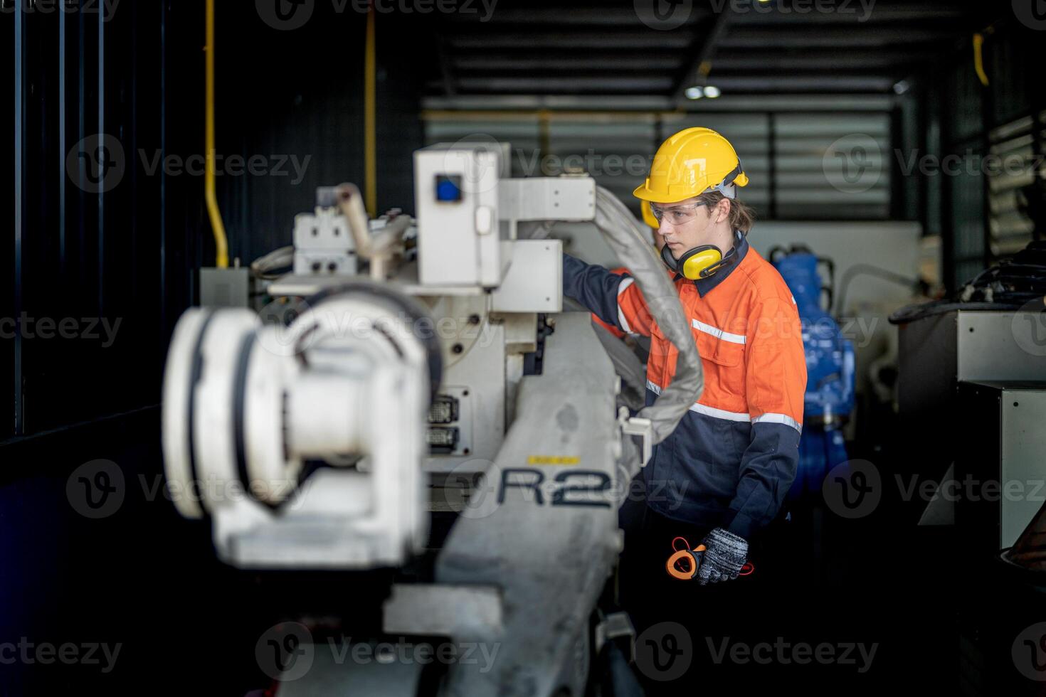 Engineer man checking the status of machine and used wrench to screw some part of equipment at CNC factory. Worker wearing safety glasses and helmet. Maintenance and repairing concept. photo