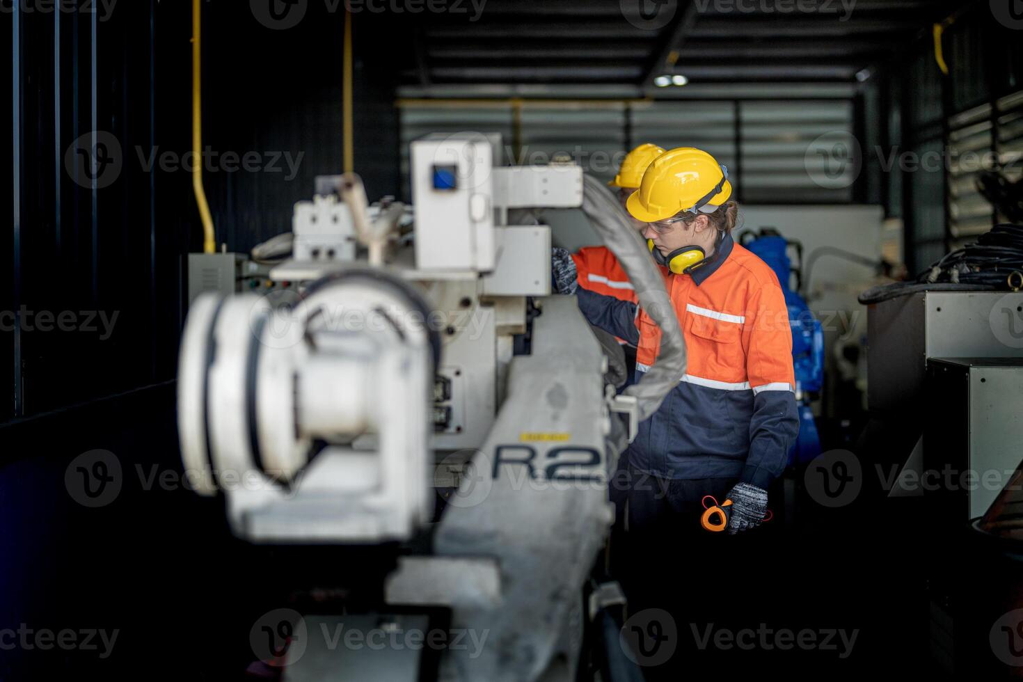 Engineer man checking the status of machine and used wrench to screw some part of equipment at CNC factory. Worker wearing safety glasses and helmet. Maintenance and repairing concept. photo