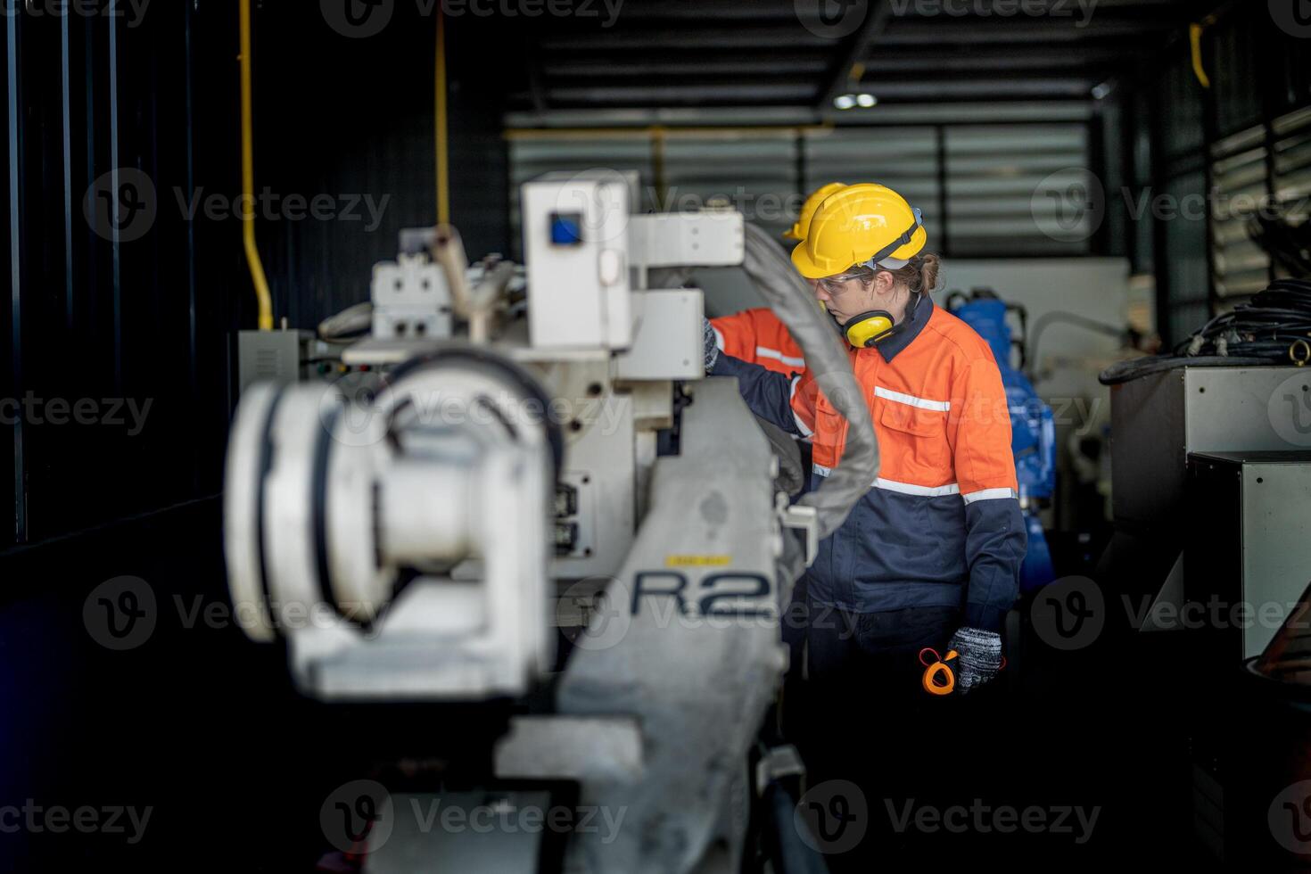 Engineer man checking the status of machine and used wrench to screw some part of equipment at CNC factory. Worker wearing safety glasses and helmet. Maintenance and repairing concept. photo