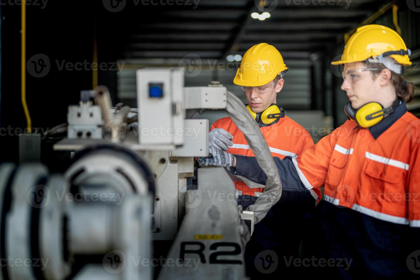 male engineer workers maintenance automatic robotic arm machine in a factory. worker checking and repairing automatic robot hand machine. technician worker check for repair factory machine. photo