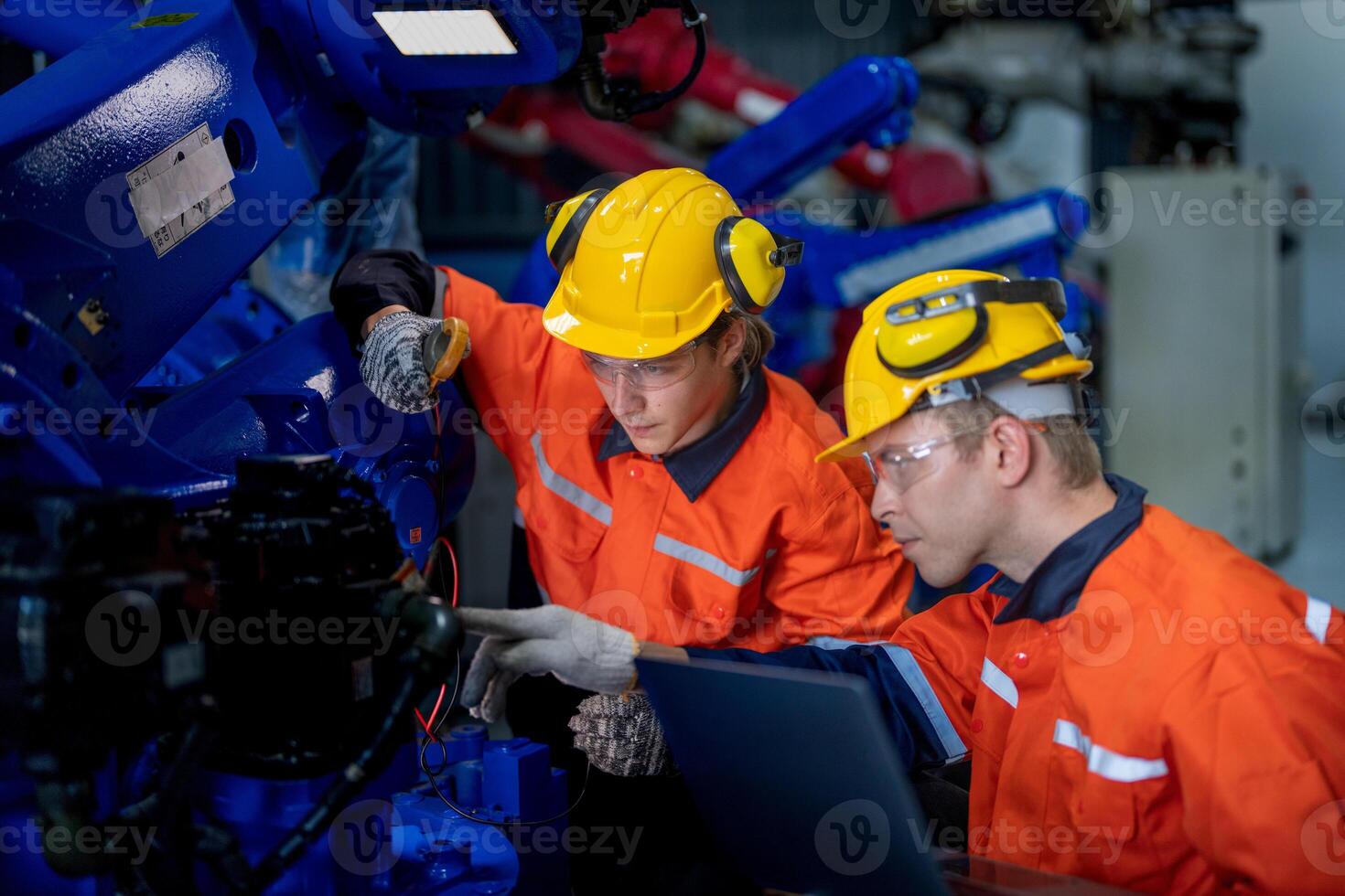 male engineer workers maintenance automatic robotic arm machine in a factory. worker checking and repairing automatic robot hand machine. technician worker check for repair factory machine. photo