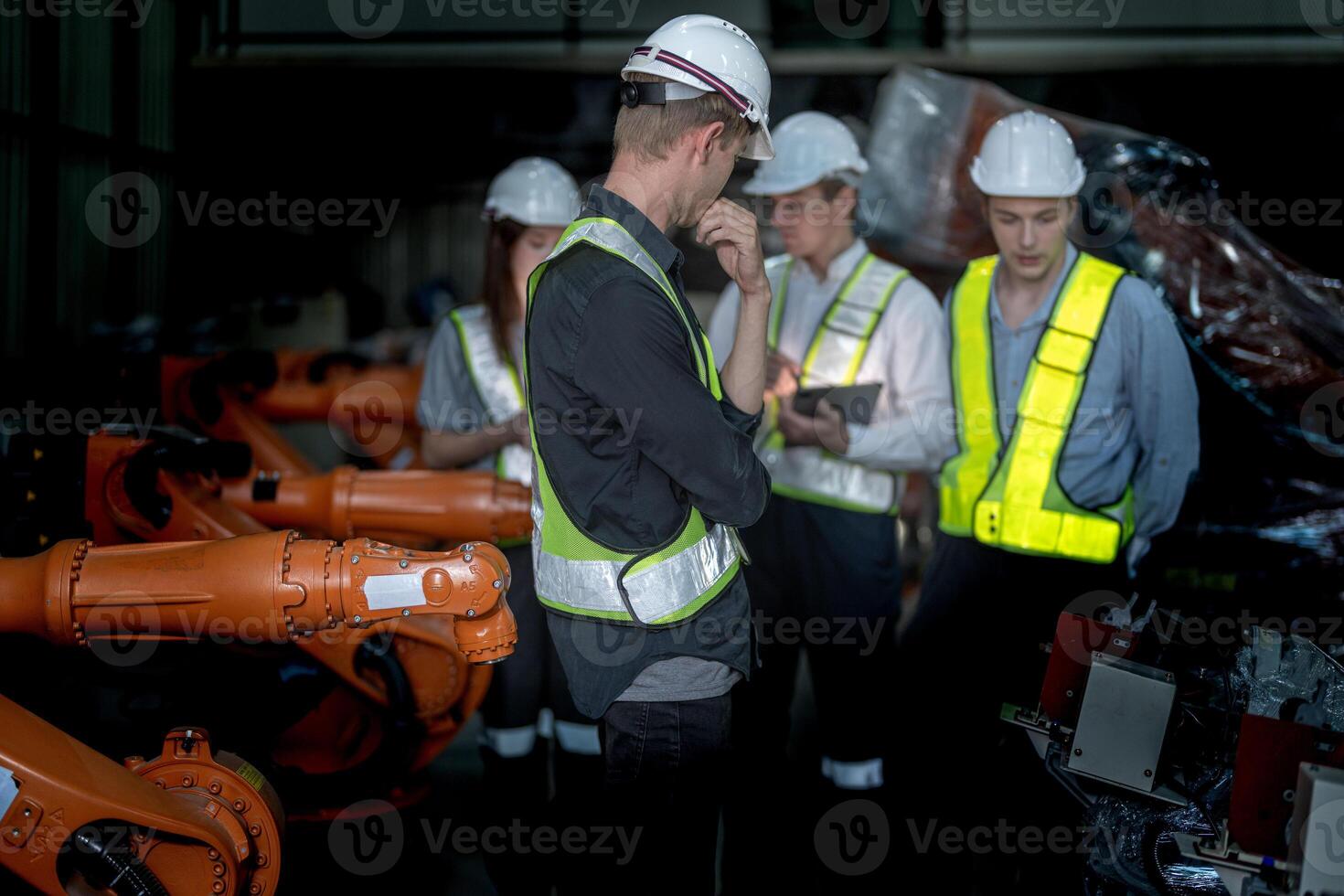 Sales manager and factory owner in suits negotiating selling robots used in the factory. Business engineers meeting and checking new machine robot. Workers walking at warehouse welding machine. photo