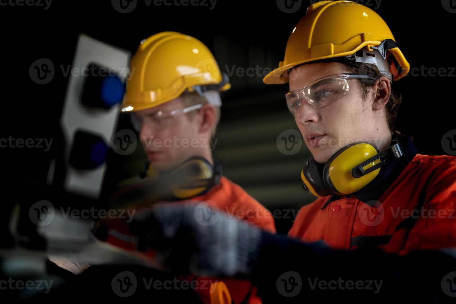 Engineer man checking the status of machine and used wrench to screw some part of equipment at CNC factory. Worker wearing safety glasses and helmet. Maintenance and repairing concept. photo