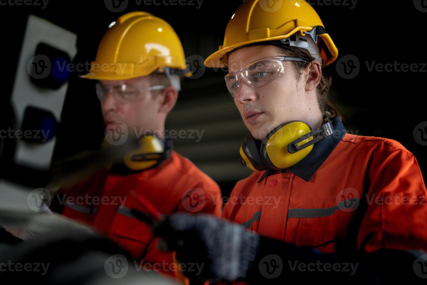 Engineer man checking the status of machine and used wrench to screw some part of equipment at CNC factory. Worker wearing safety glasses and helmet. Maintenance and repairing concept. photo