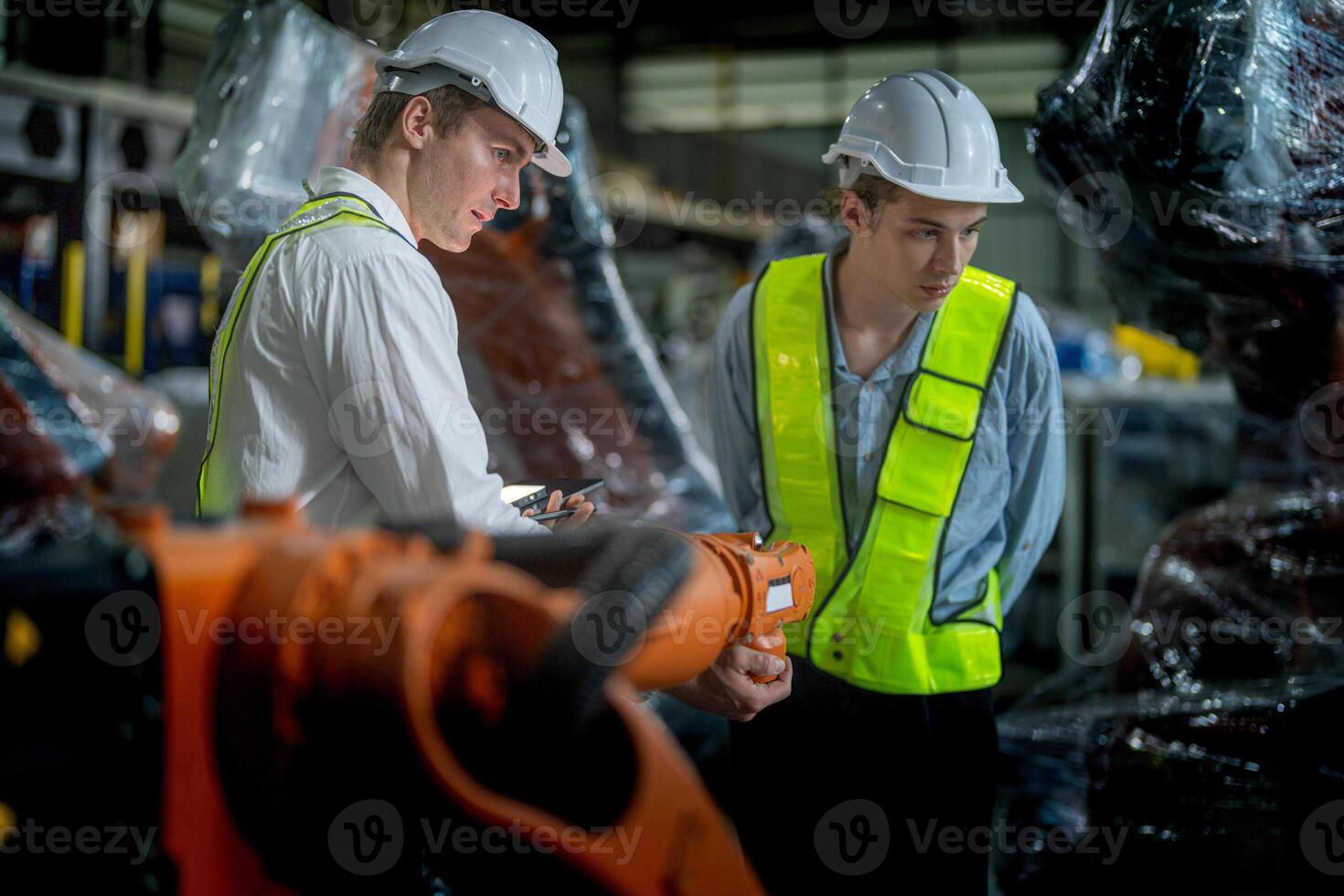 Business engineers meeting and checking new machine robot. Workers walking at warehouse industry welding machine. business negotiation concepts and technology. women Using smart Tablet to present man. photo