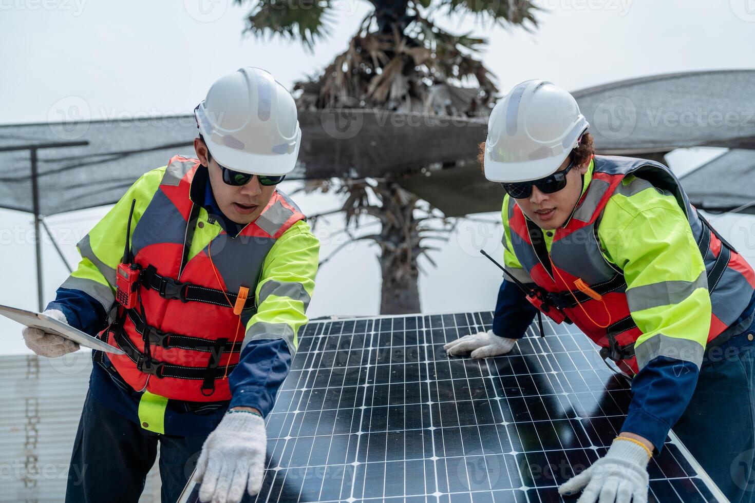 engineer men inspect modules of photovoltaic cell panels. Industrial Renewable energy of green power. workers prepare materials before construction on site with the stack of panels at background. photo