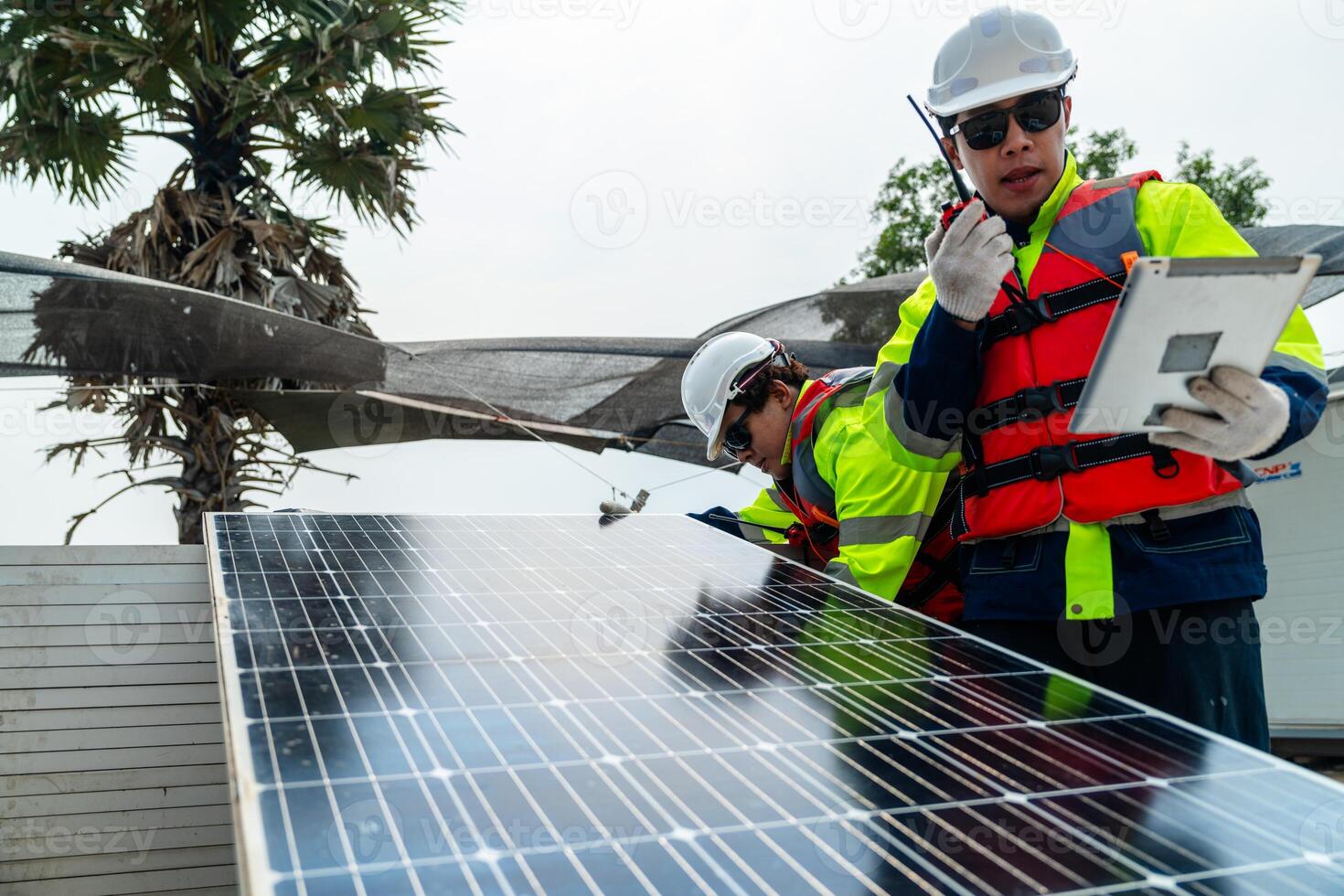 engineer men inspect modules of photovoltaic cell panels. Industrial Renewable energy of green power. workers prepare materials before construction on site with the stack of panels at background. photo