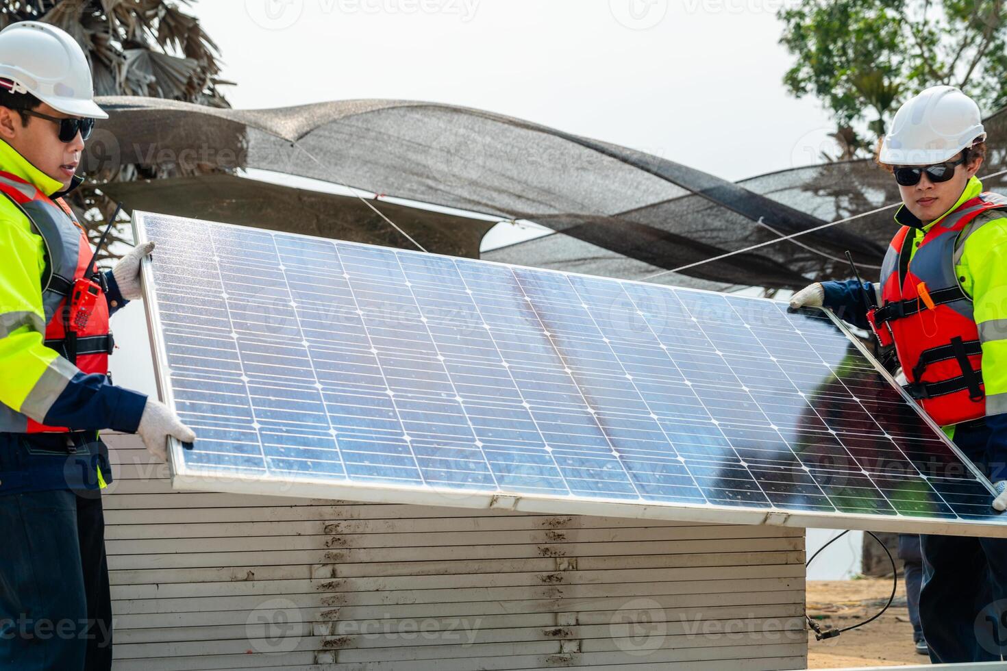 engineer men inspect modules of photovoltaic cell panels. Industrial Renewable energy of green power. workers prepare materials before construction on site with the stack of panels at background. photo