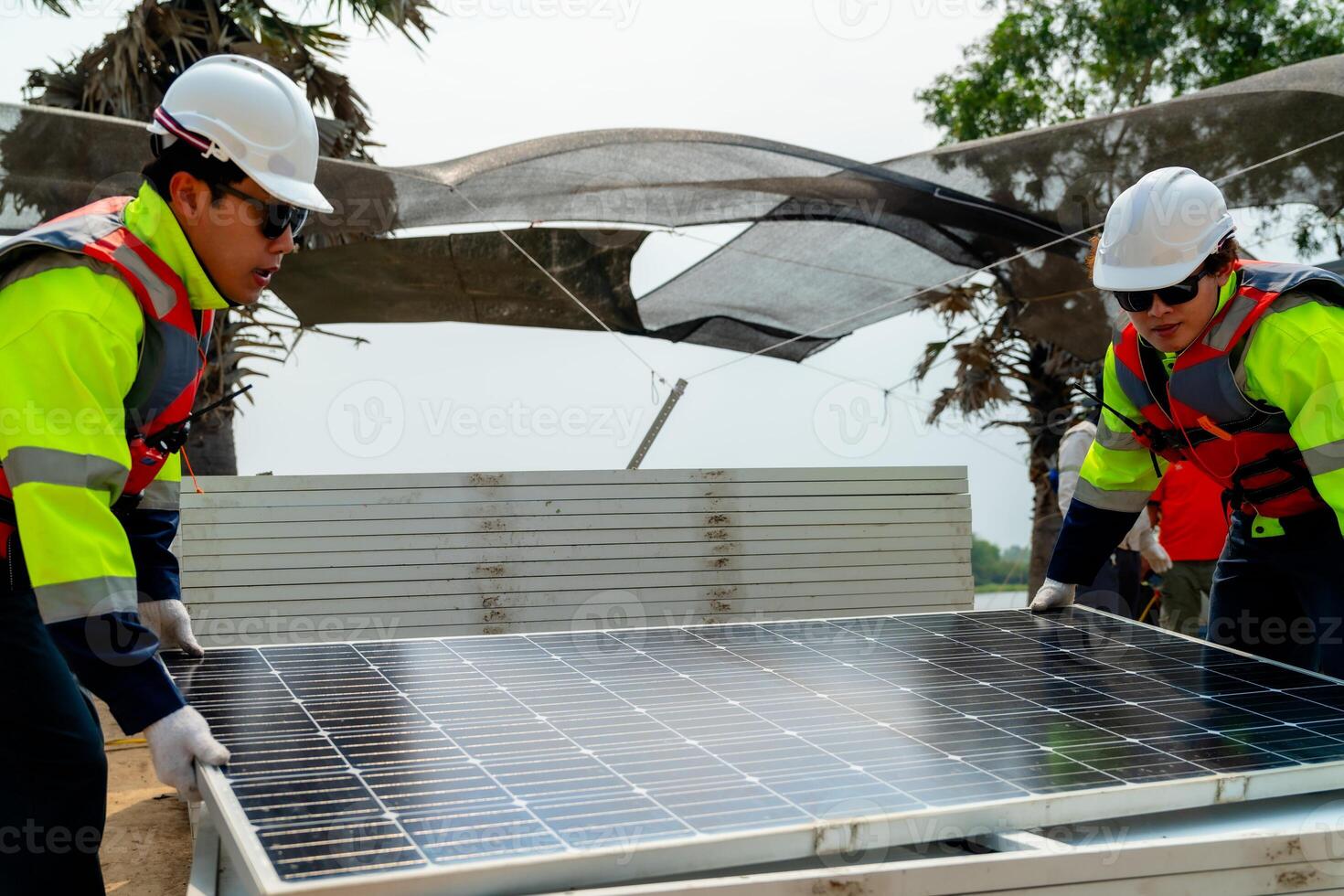 engineer men inspect modules of photovoltaic cell panels. Industrial Renewable energy of green power. workers prepare materials before construction on site with the stack of panels at background. photo