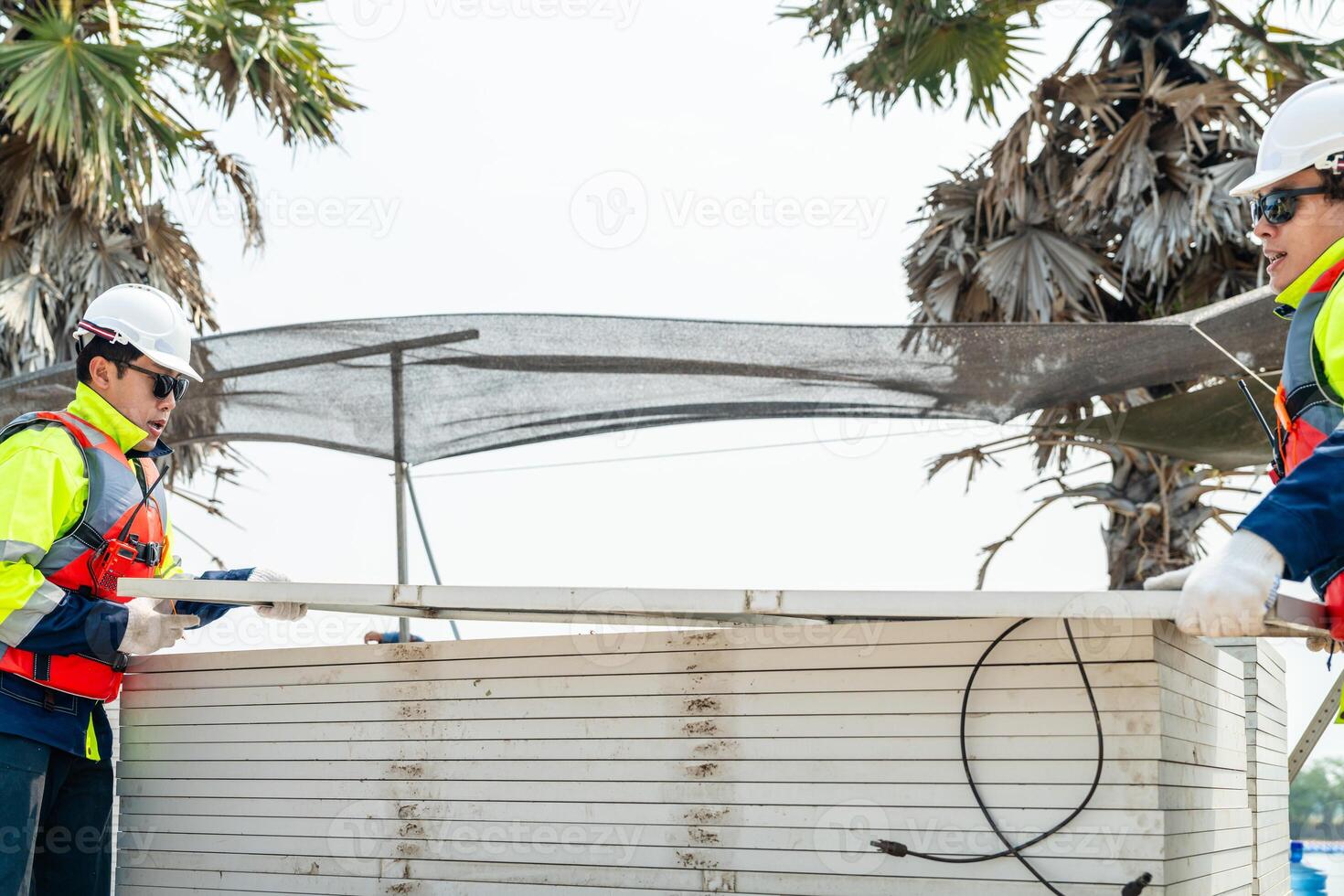 engineer men inspect modules of photovoltaic cell panels. Industrial Renewable energy of green power. workers prepare materials before construction on site with the stack of panels at background. photo