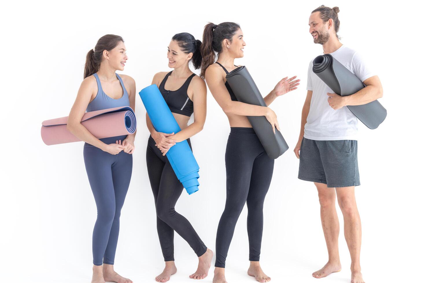 Group of happy sporty women and guy wearing body stylish sportswear holding personal carpets leaned on a white background. waiting for yoga class or body weight class. healthy lifestyle and wellness photo