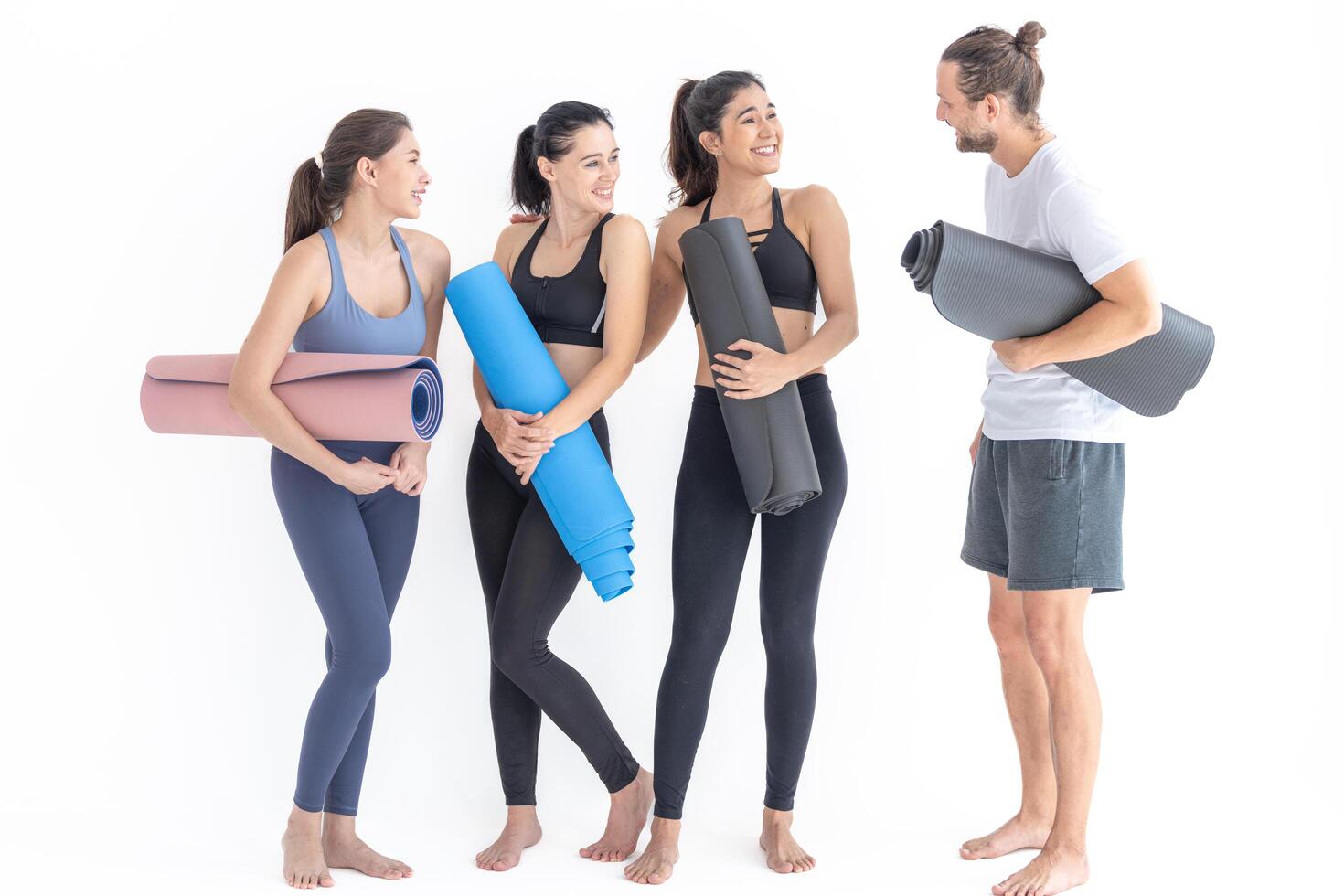 grupo de contento deportivo mujer y chico vistiendo cuerpo elegante ropa de deporte participación personal alfombras inclinado en un blanco antecedentes. esperando para yoga clase o cuerpo peso clase. sano estilo de vida y bienestar foto