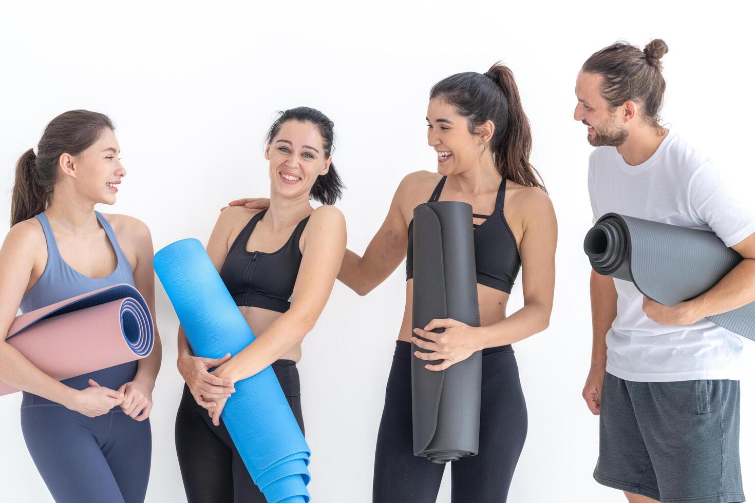 grupo de contento deportivo mujer hablando con cuerpo elegante ropa de deporte participación personal alfombras inclinado en un blanco antecedentes. esperando para yoga clase o cuerpo peso clase. sano estilo de vida y bienestar foto