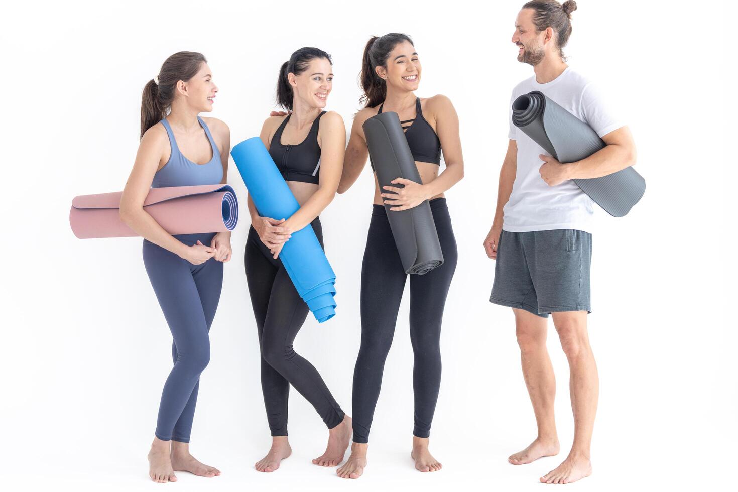 Group of happy sporty women and guy wearing body stylish sportswear holding personal carpets leaned on a white background. waiting for yoga class or body weight class. healthy lifestyle and wellness photo