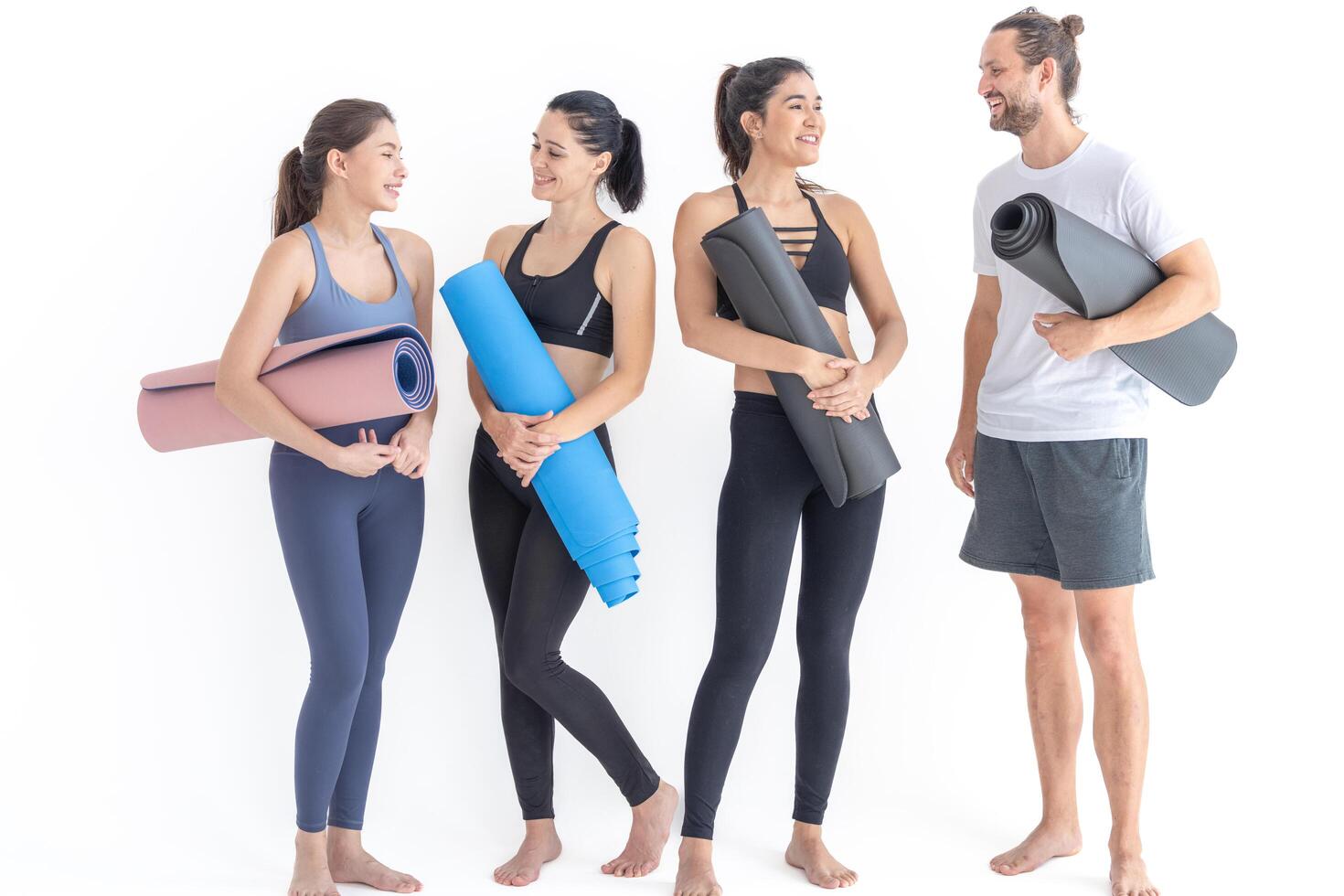 Group of happy sporty women and guy wearing body stylish sportswear holding personal carpets leaned on a white background. waiting for yoga class or body weight class. healthy lifestyle and wellness photo