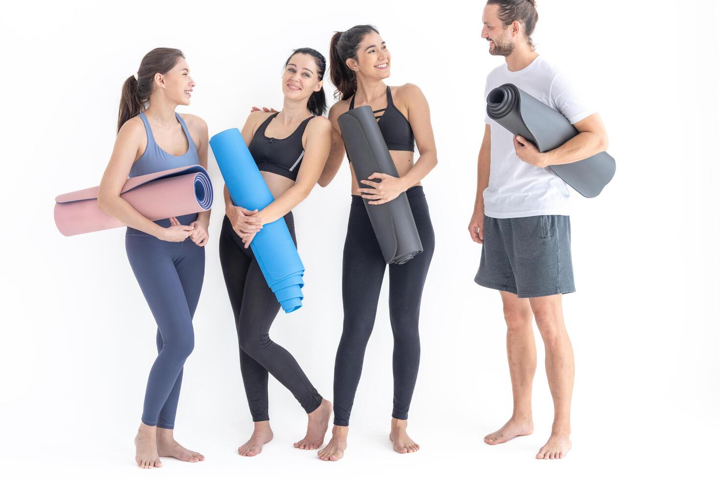 Group of happy sporty women and guy wearing body stylish sportswear holding personal carpets leaned on a white background. waiting for yoga class or body weight class. healthy lifestyle and wellness photo