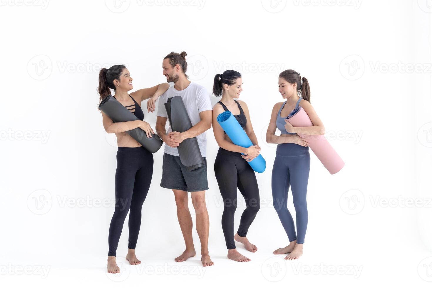 Group of happy sporty girls and guy wearing body stylish sportswear holding personal carpets leaned on a white background. waiting for yoga class or body weight class. healthy lifestyle and wellness photo