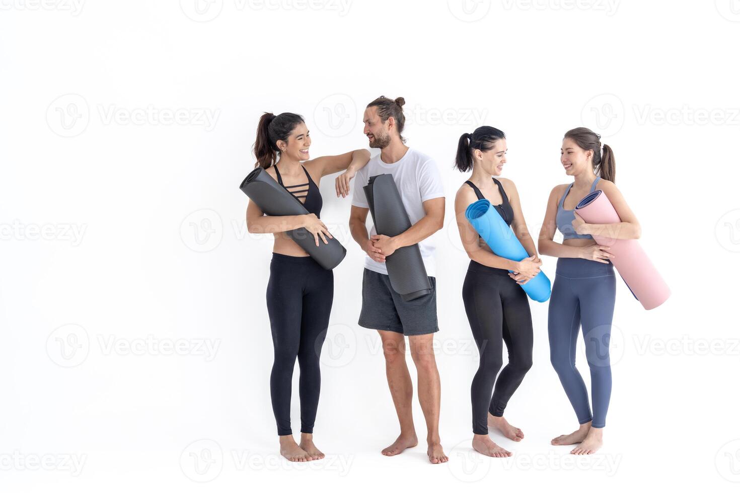 grupo de contento deportivo muchachas y chico vistiendo cuerpo elegante ropa de deporte participación personal alfombras inclinado en un blanco antecedentes. esperando para yoga clase o cuerpo peso clase. sano estilo de vida y bienestar foto