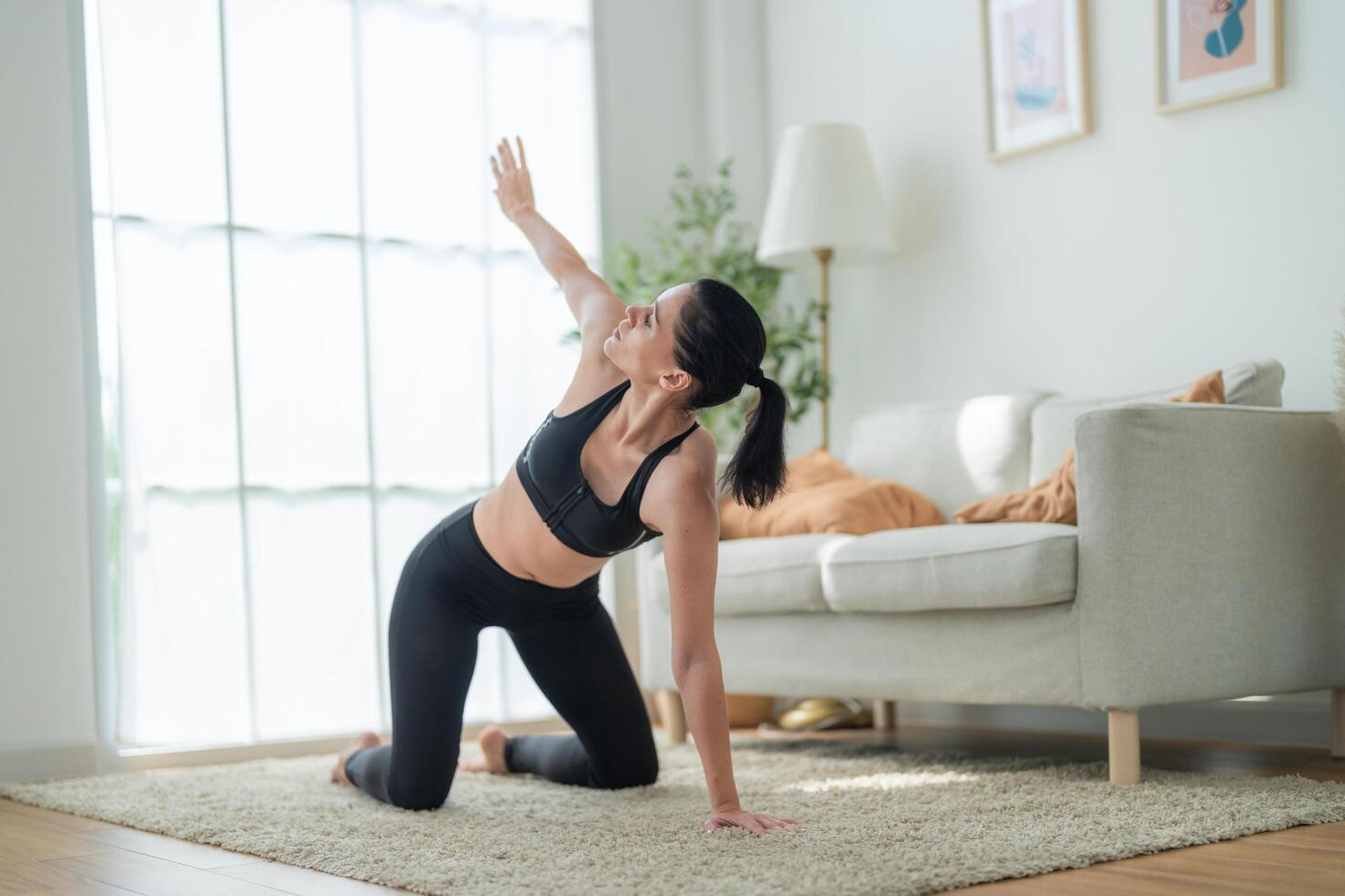 cerca arriba mujer confidente formación yoga. atlético mujer en ropa de deporte haciendo aptitud extensión ejercicios a hogar en el vivo habitación. deporte y recreación concepto. yoga profesor es Ayudar muchacha. foto