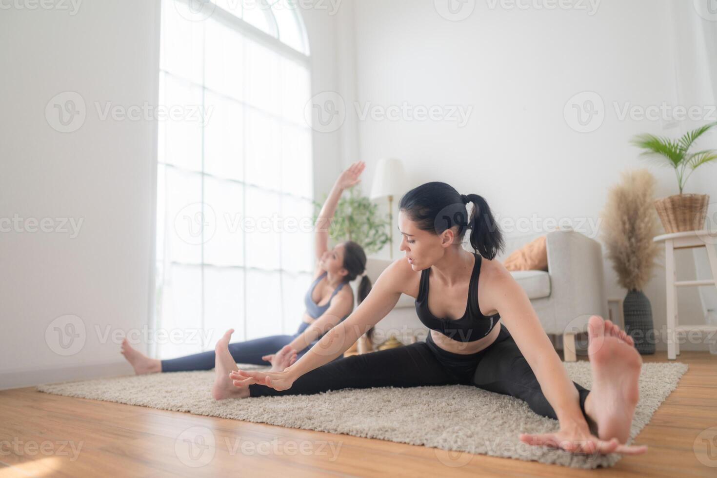 Two women confident training yoga. Athletic women in sportswear doing fitness stretching exercises at home in the living room. Sport and recreation concept. Yoga teacher is helping young woman. photo