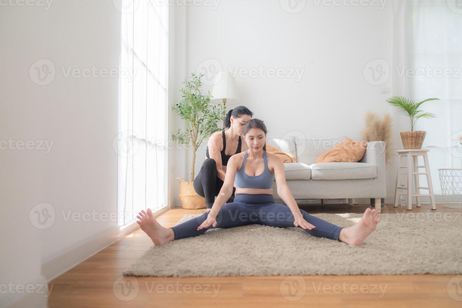 Two women confident training yoga. Athletic women in sportswear doing fitness stretching exercises at home in the living room. Sport and recreation concept. Yoga teacher is helping young woman. photo