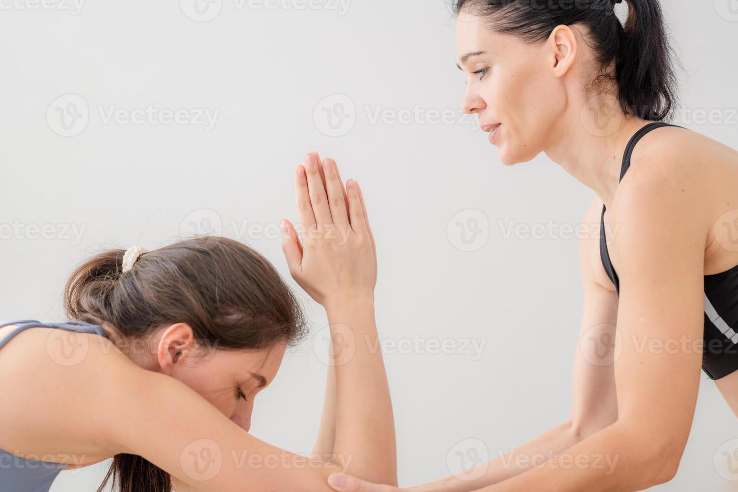 Two women confident training yoga. Athletic women in sportswear doing fitness stretching exercises at home in the living room. Sport and recreation concept. Yoga teacher is helping young woman. photo