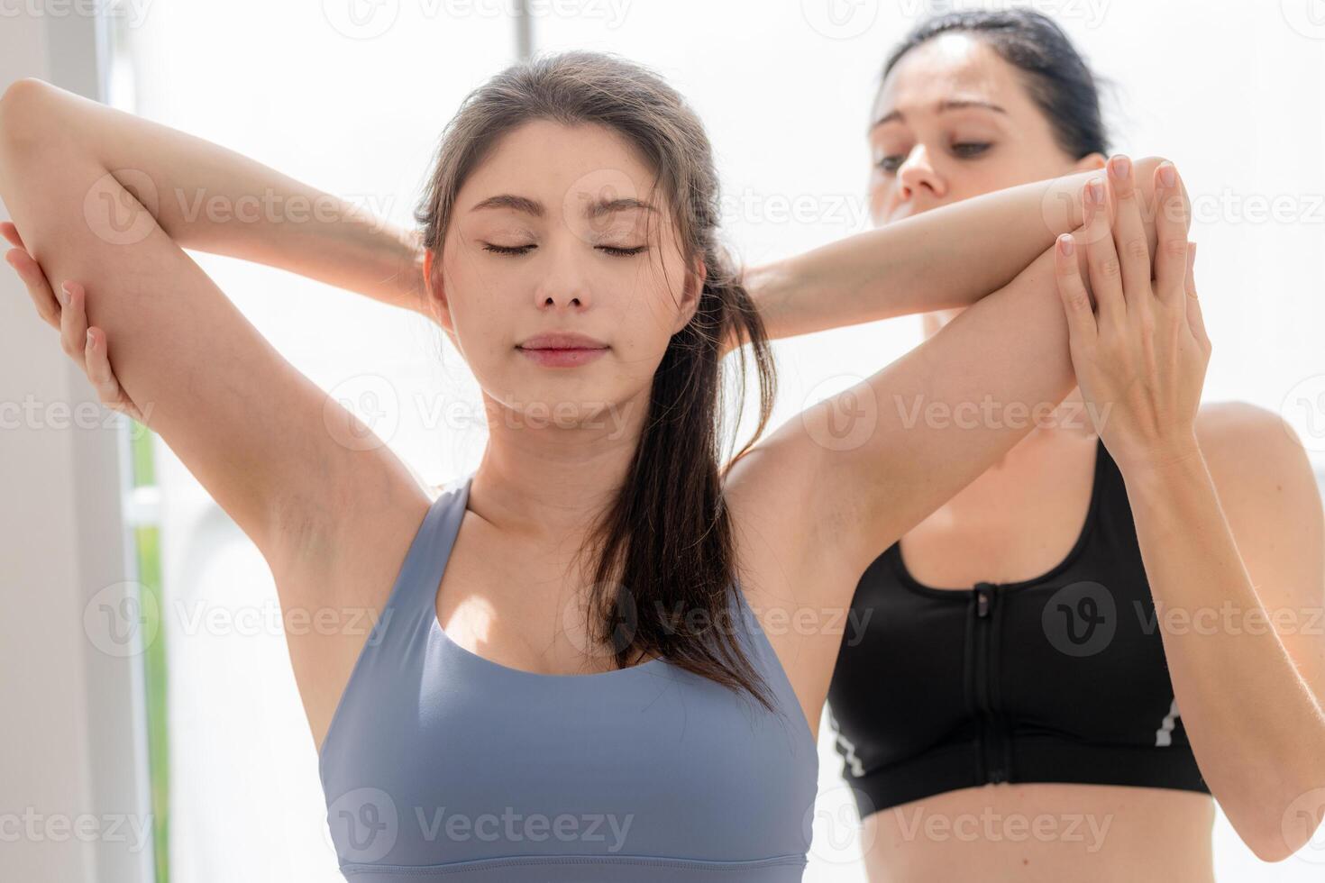 close up women confident training yoga. Athletic women in sportswear doing fitness stretching exercises at home in the living room. Sport and recreation concept. Yoga teacher is helping girl. photo