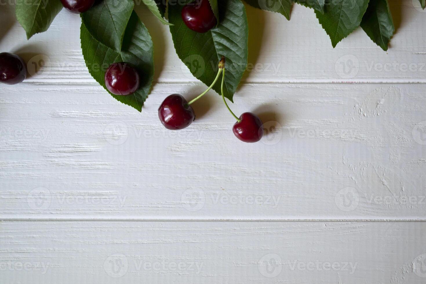 The branch with ripe cherries on a white wooden background. photo