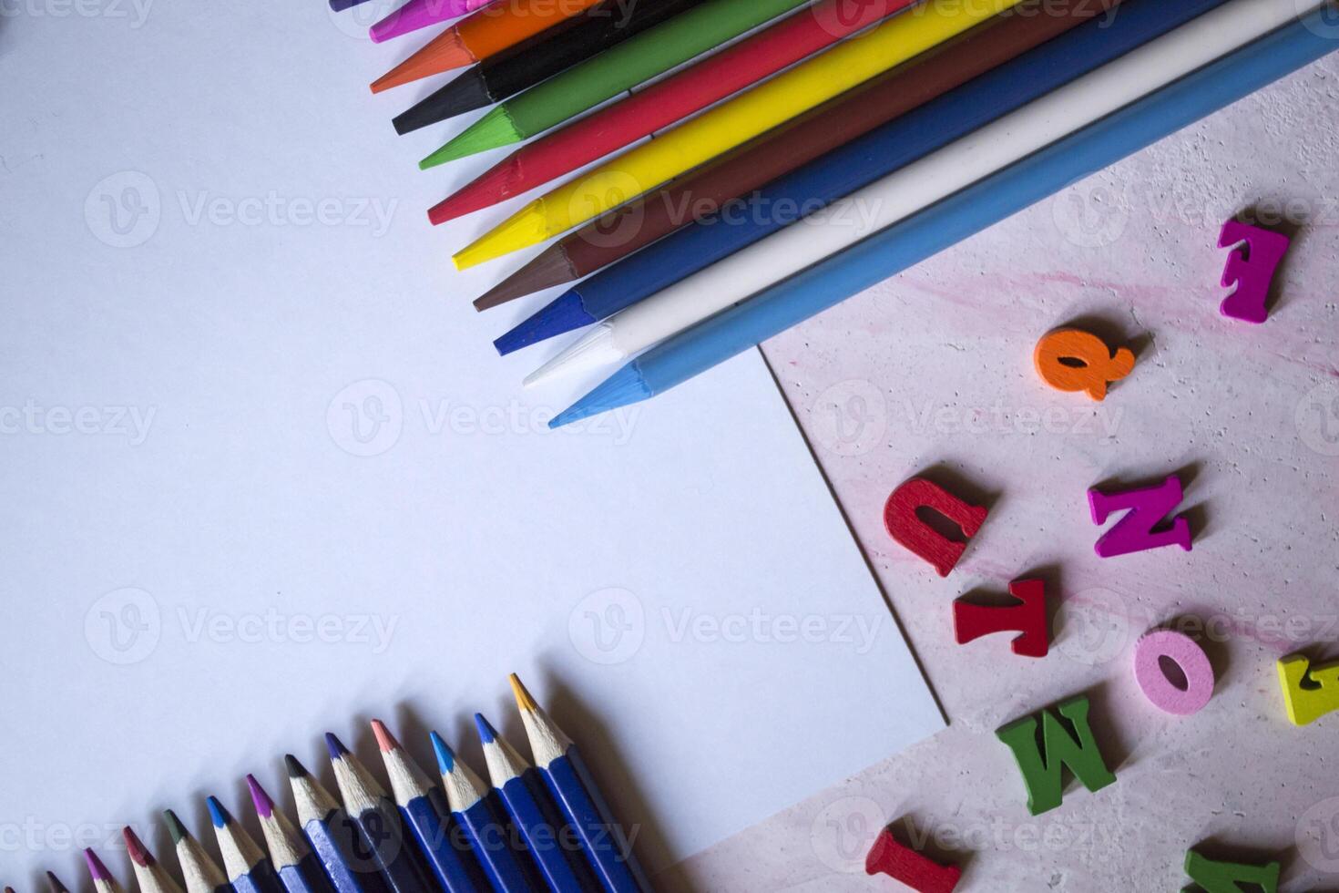 multicolor letras y conjunto de lapices en el mesa. vistoso de madera alfabeto y lapices en un mesa. foto