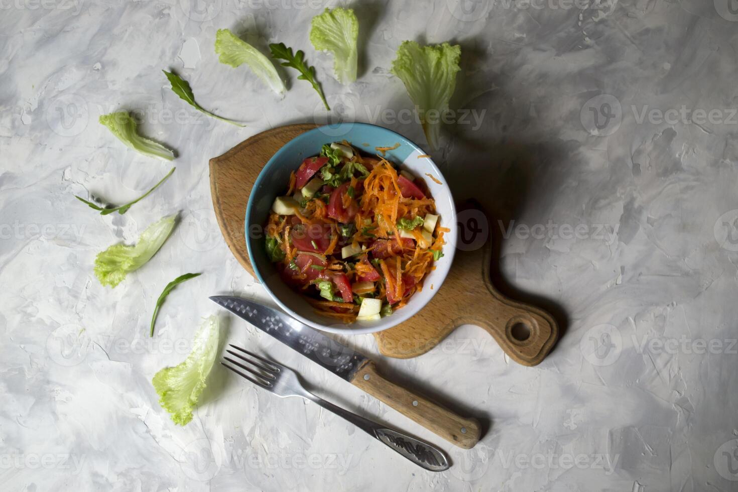 The bowl of organic salad and cutlery on a table. photo